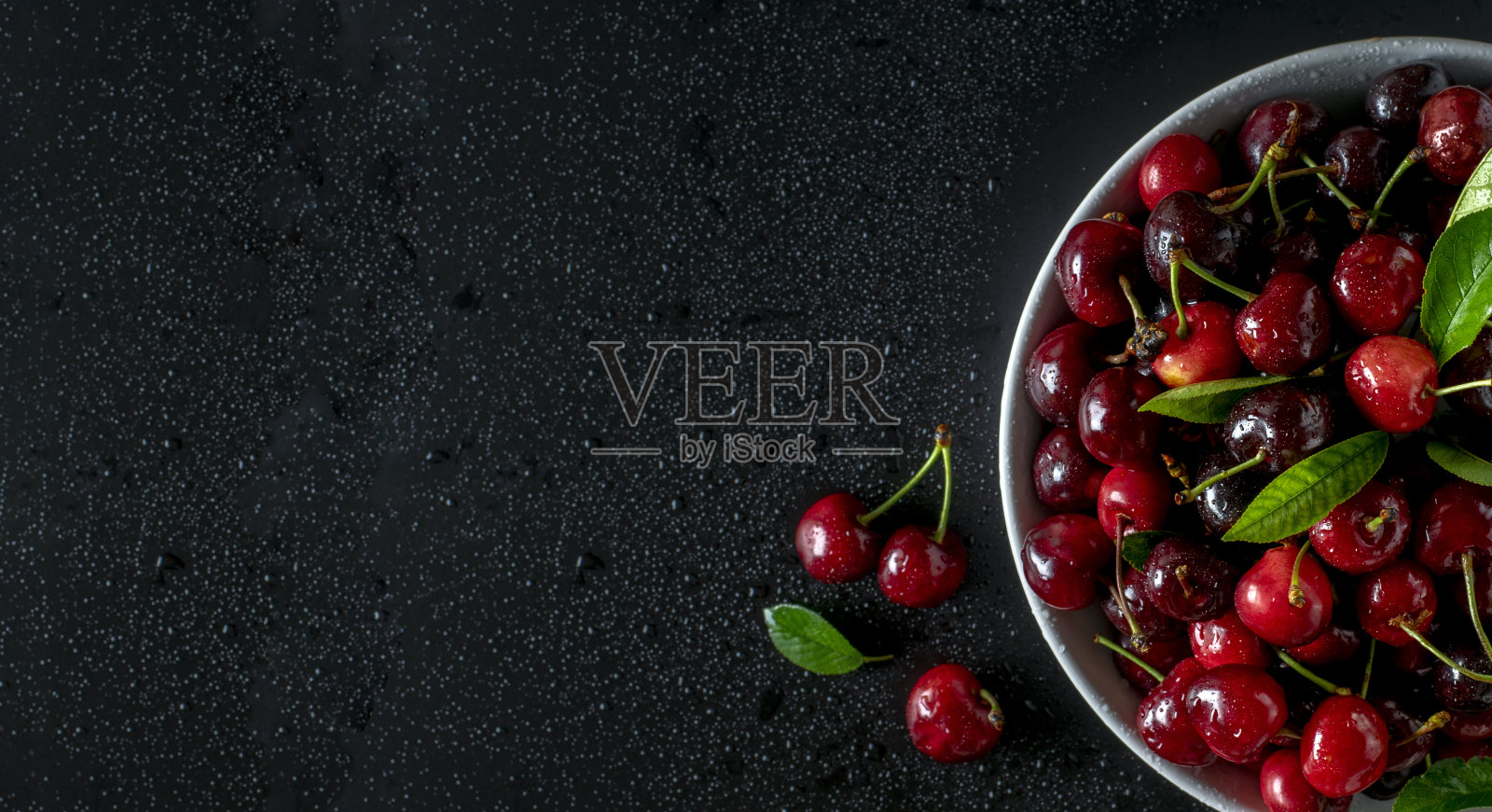 樱桃在碗里，在黑色的背景和水滴，复制空间。照片摄影图片