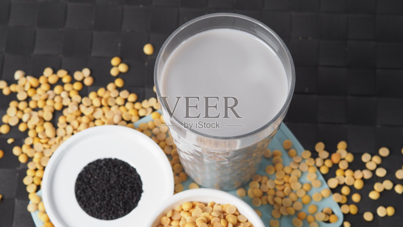 黑芝麻和豆浆混合在透明玻璃上，黑芝麻和黄豆在一个杯子里。黑芝麻豆浆。健康饮料与天然成分。豆浆喝。照片摄影图片