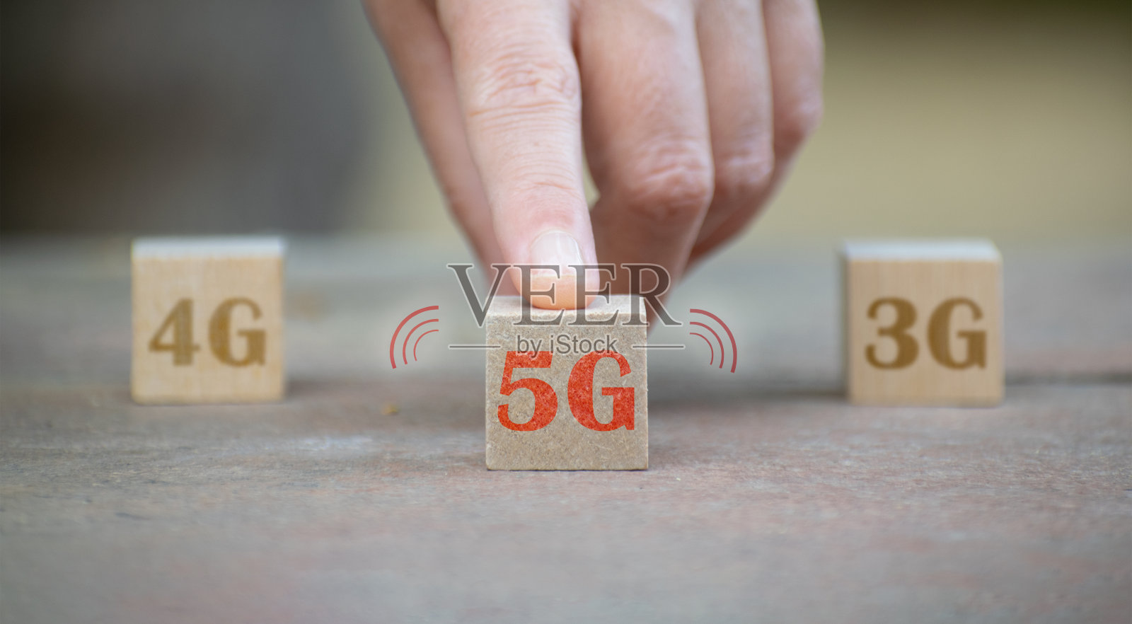 5G(第五代)网络概念。有选择的关注女性手指推立方体5G图标和两个模糊的4G和3G立方体。照片摄影图片