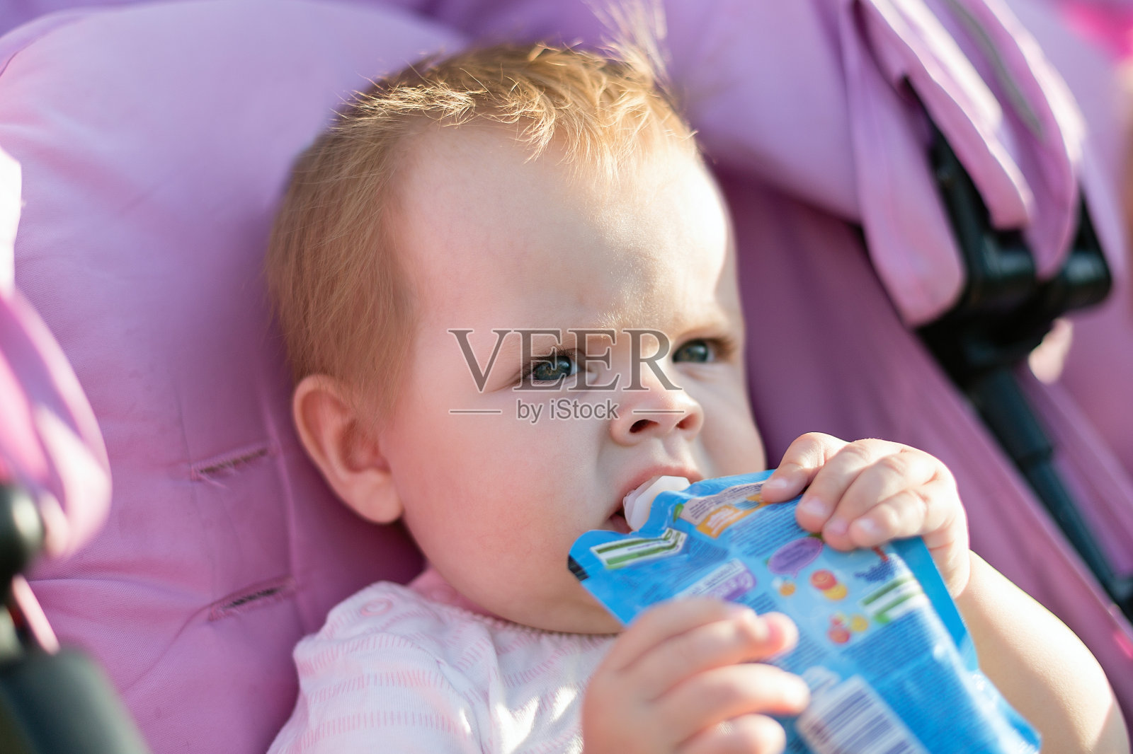 一个散步的小孩在婴儿车里吃午饭照片摄影图片