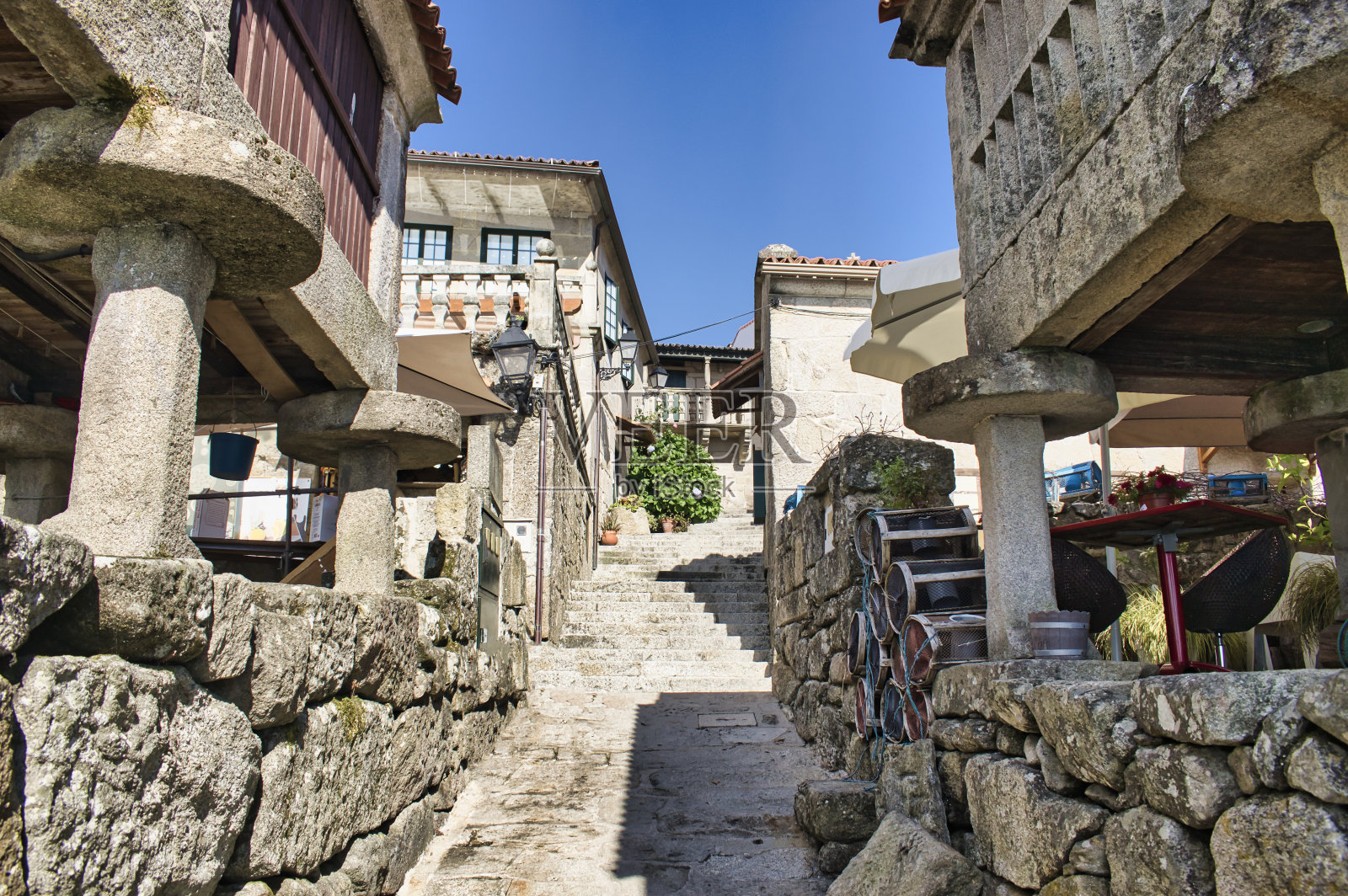 西班牙Combarro村狭窄的步行街，有楼梯和传统的加利西亚基粒，用柱子支撑照片摄影图片