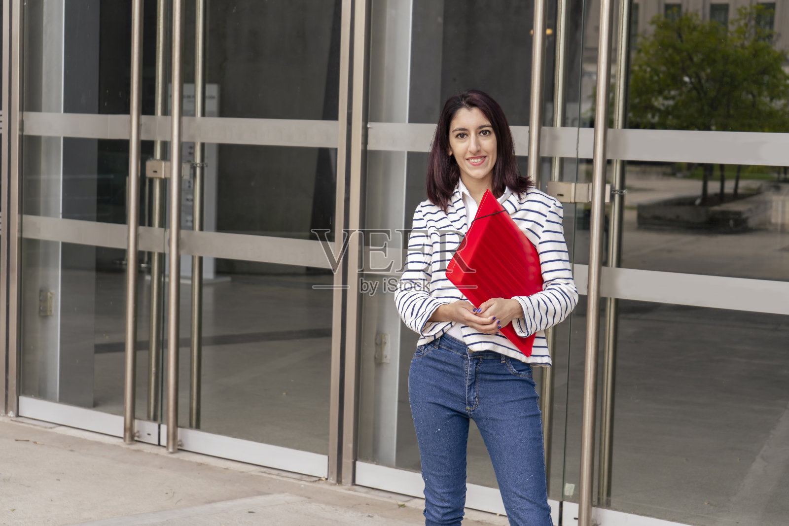 年轻的拉丁女商人站在她公司大楼外的门口。成功,经营理念。照片摄影图片