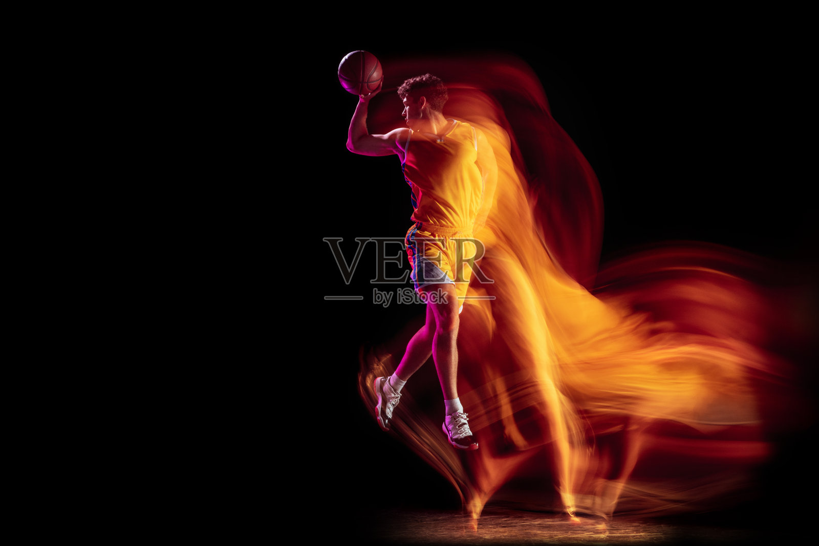 年轻的白人篮球运动员训练孤立的黑色背景在混合霓虹灯。照片摄影图片