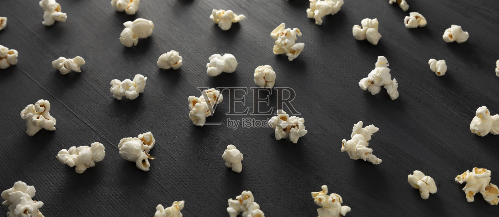 爆米花在黑色背景上排成一排。照片摄影图片