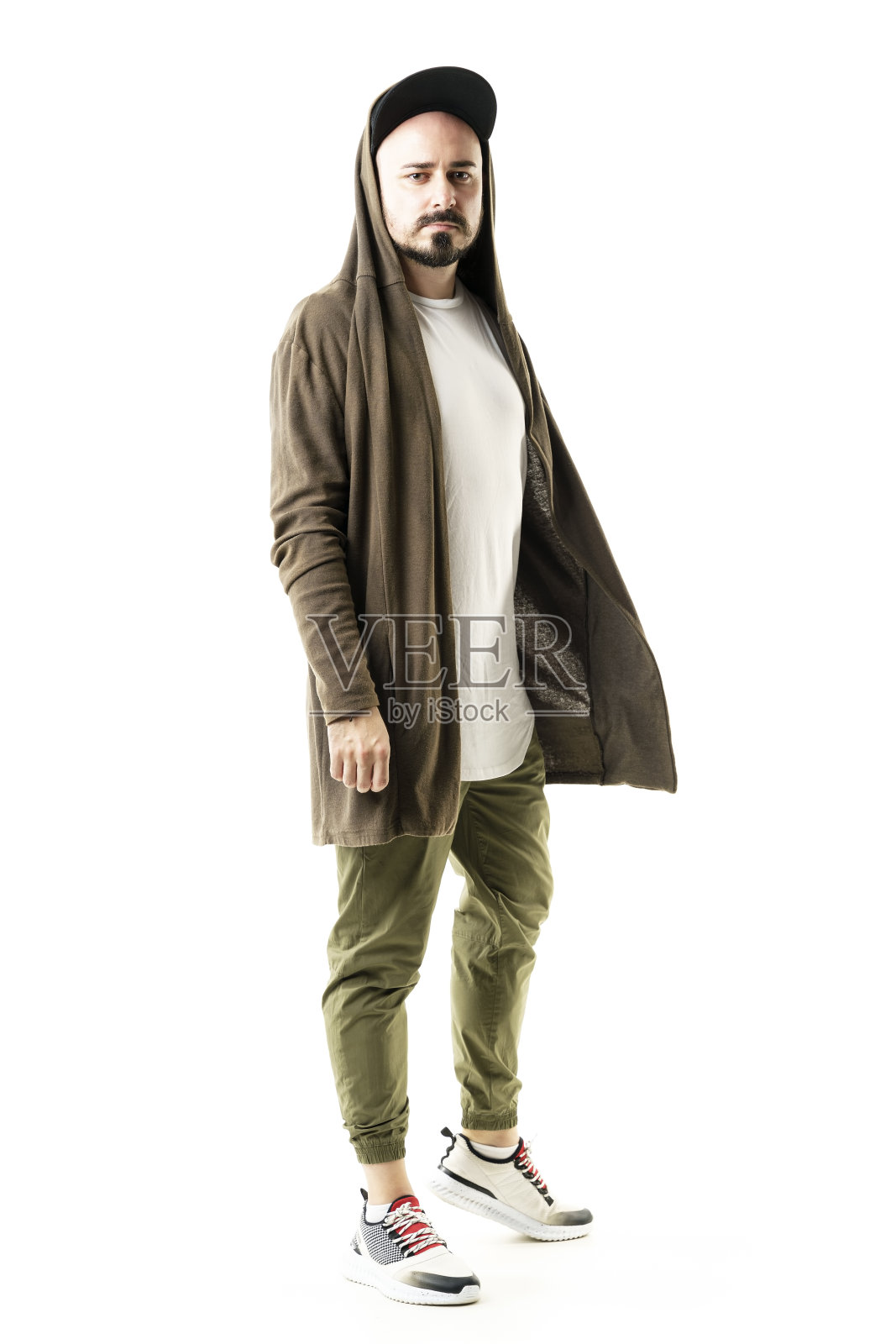 酷独特的时尚男人穿着长连帽羊毛衫和棒球帽看着相机。照片摄影图片