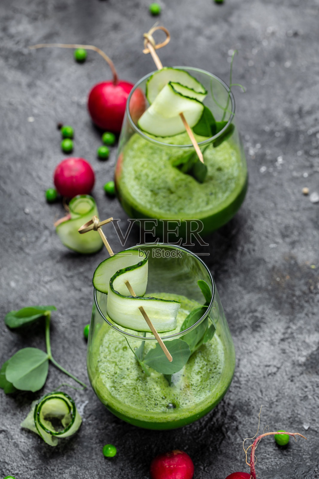 两杯绿色冰沙，配新鲜青豆、黄瓜、萝卜、菠菜和青柠。垂直的图像。俯视图照片摄影图片
