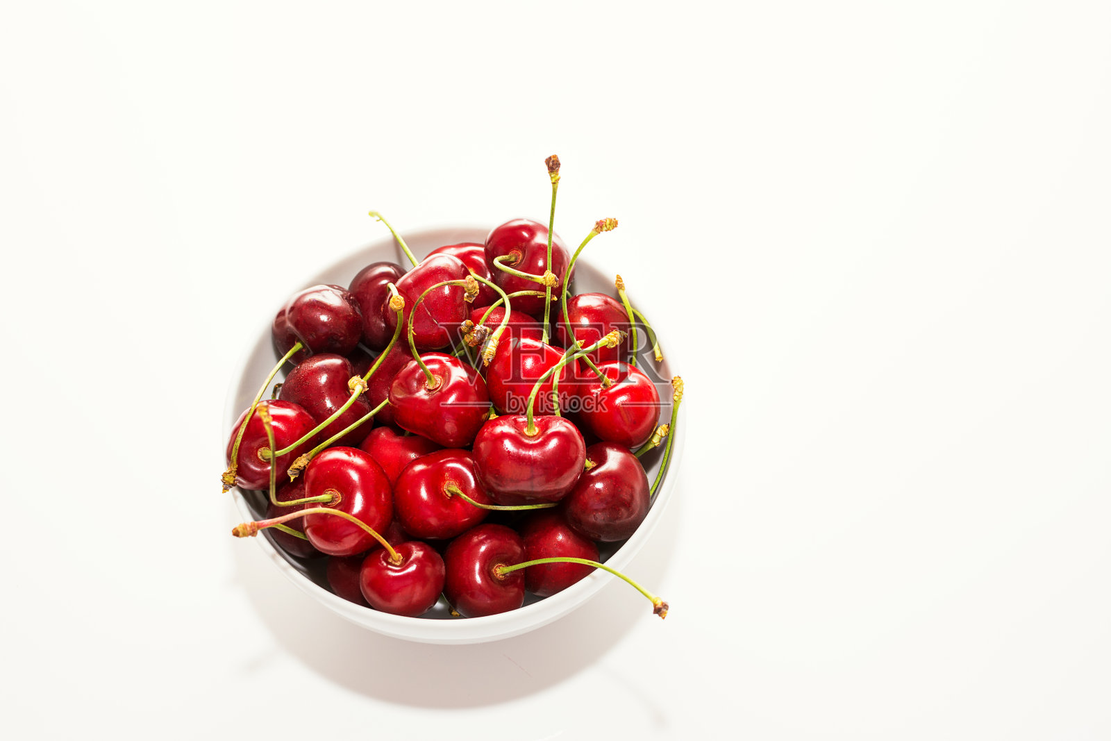 白色背景的白色杯子里的红色樱桃照片摄影图片