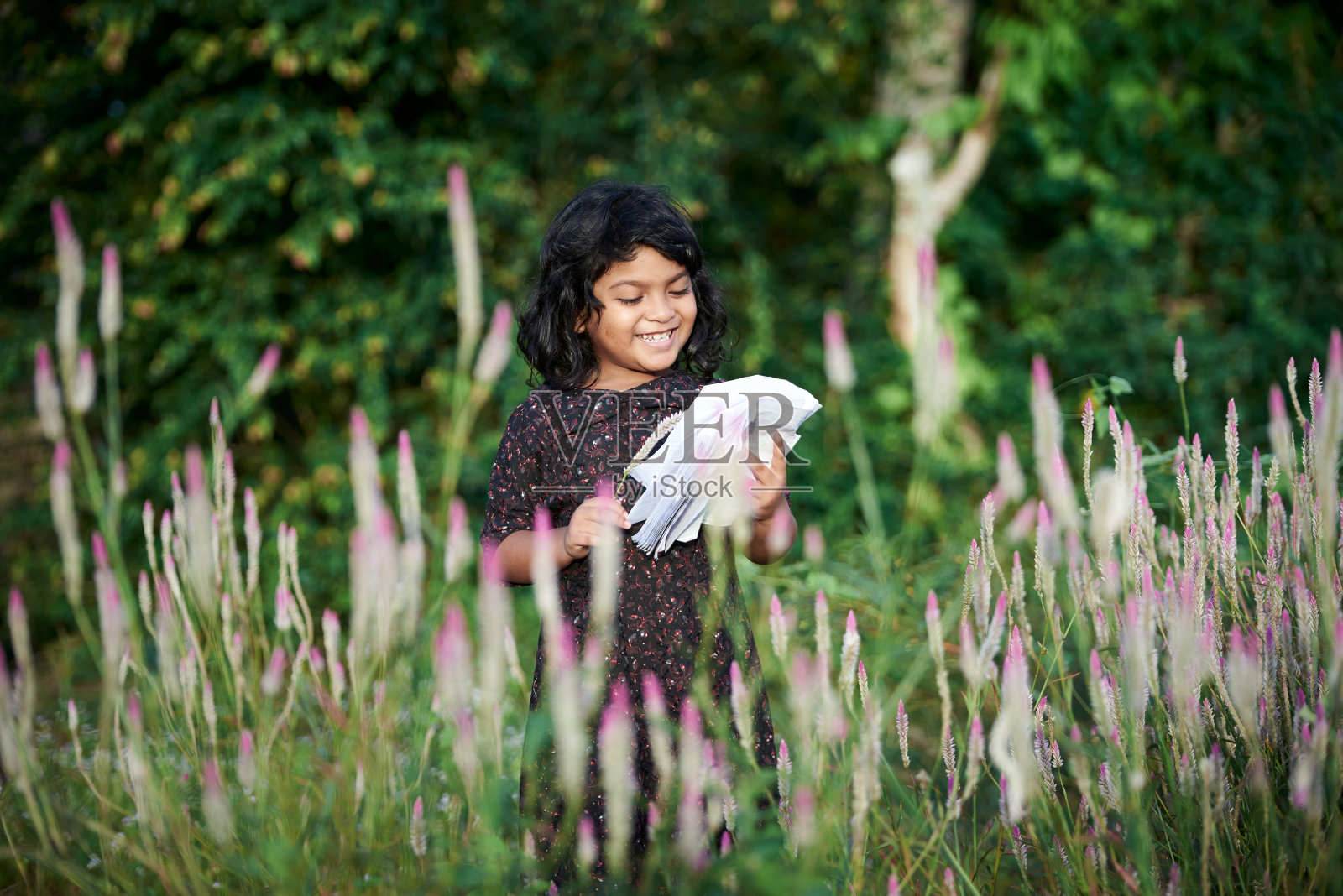 一个亚洲女学生在自然公园看书和独自玩耍照片摄影图片