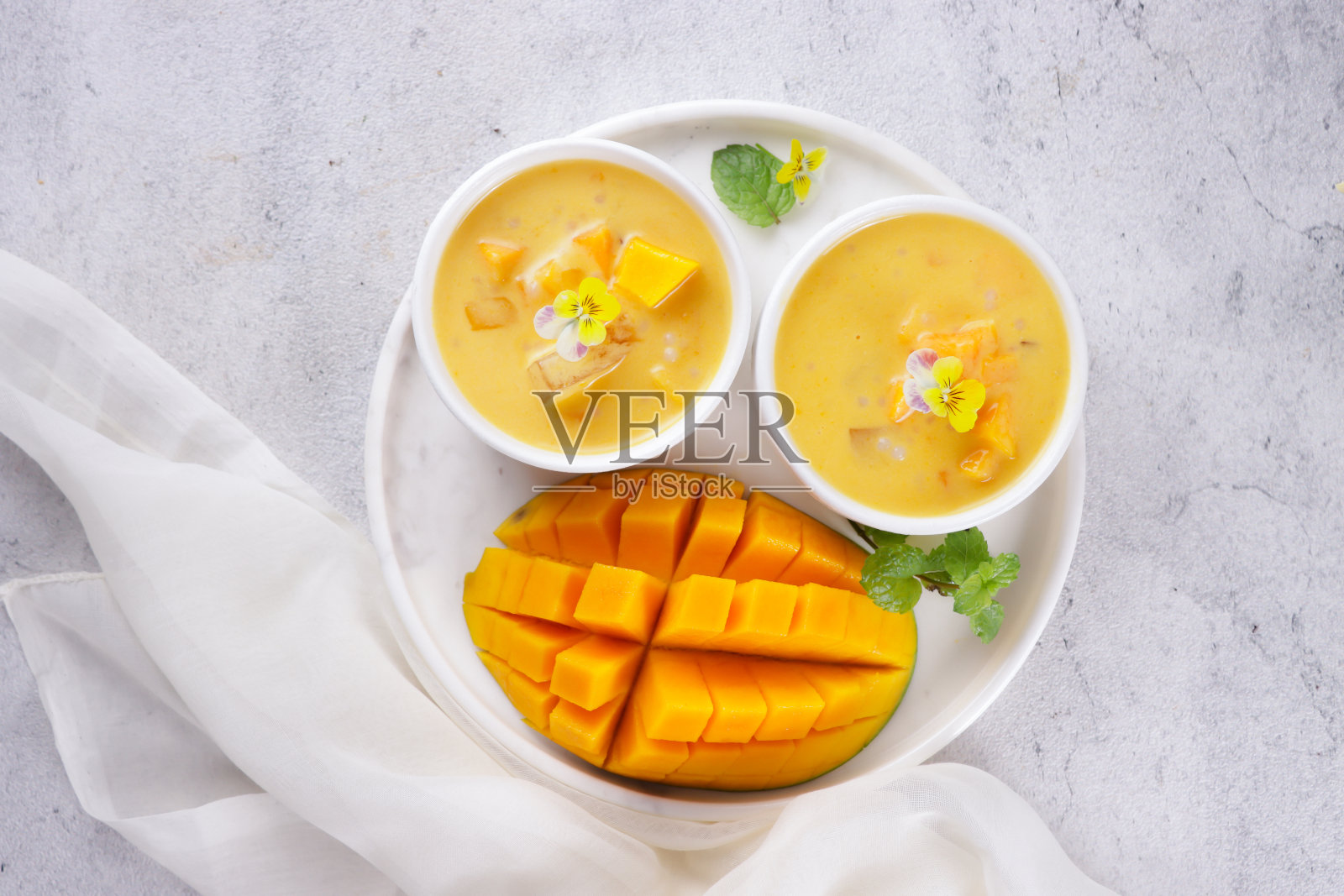 芒果西米。甜西米奶油芒果，椰奶和芒果汁装饰可食用的花。照片摄影图片