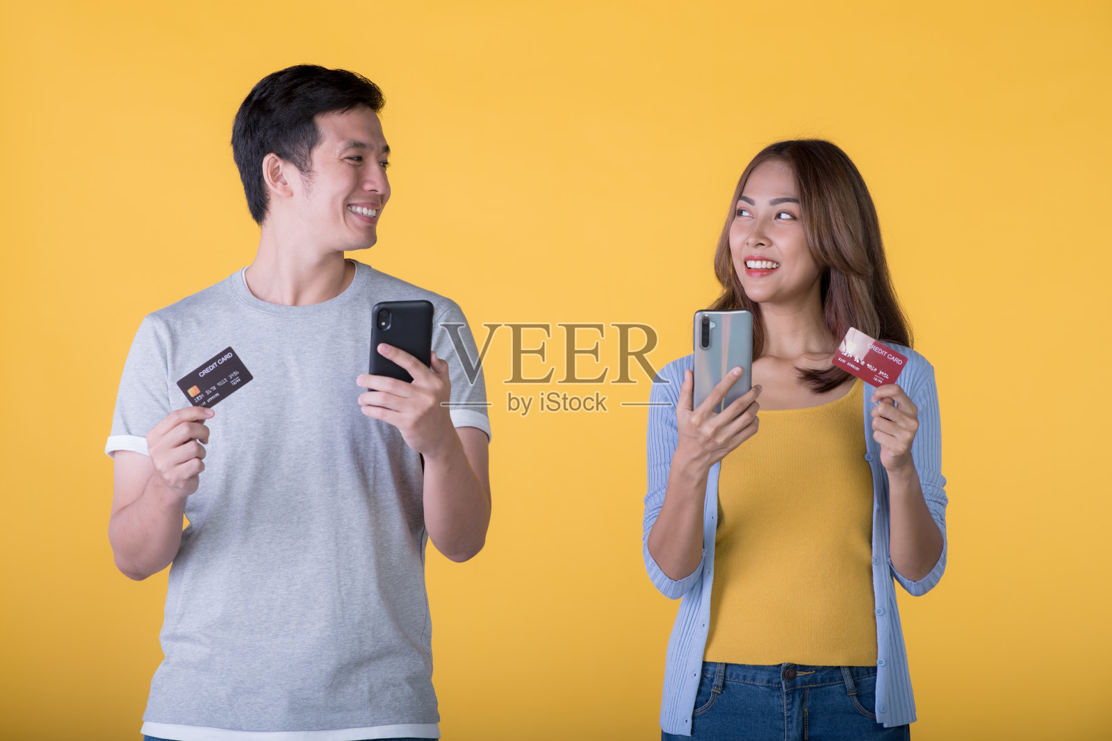 兴奋的亚洲夫妇拿着信用卡和智能手机感觉兴奋孤立在彩色背景照片摄影图片