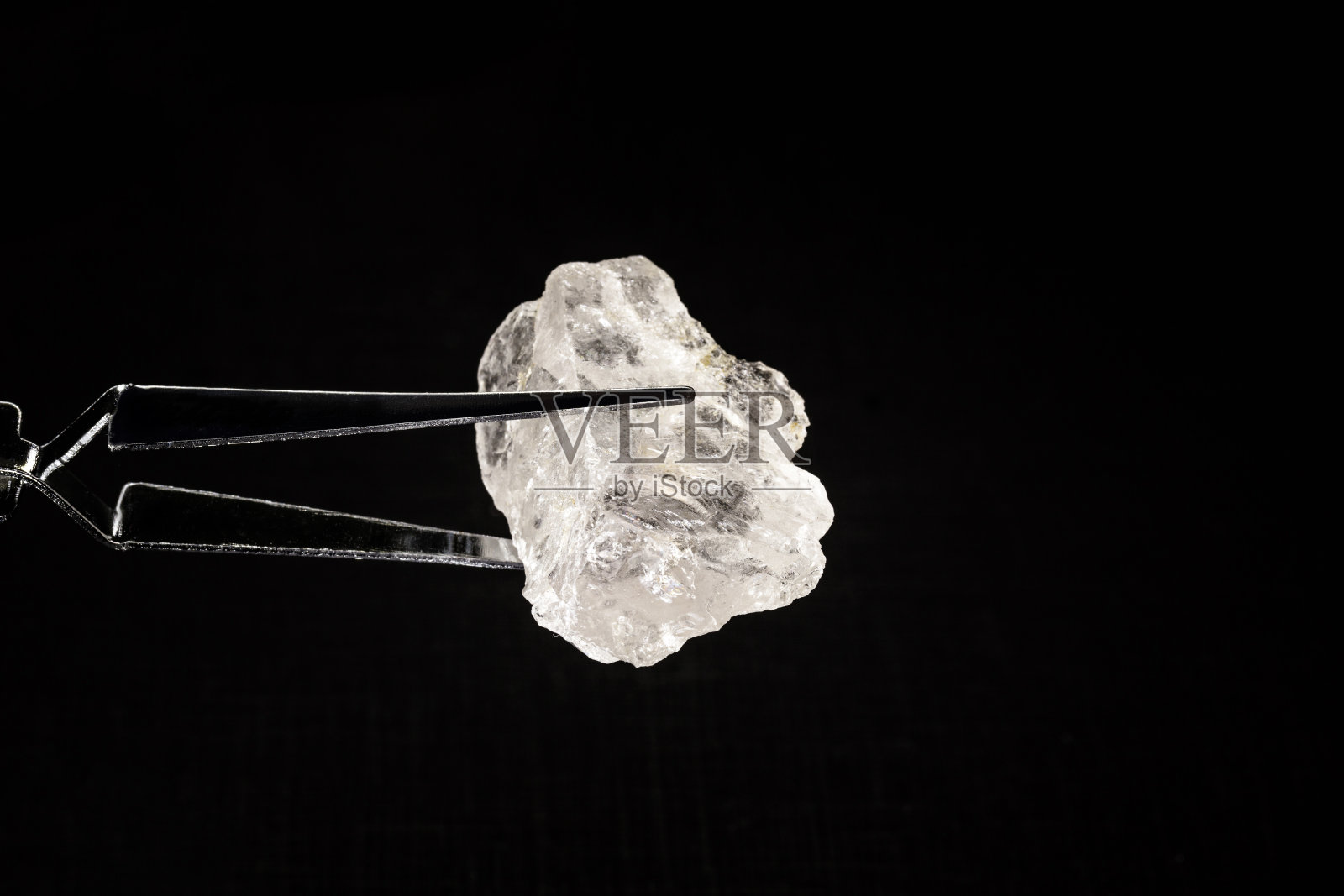 用珠宝商的镊子夹着未经加工的钻石或水晶，背景上是珠宝，聚焦照片摄影图片