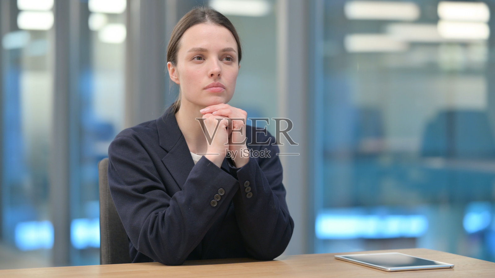 沉思的年轻女商人坐在办公室里思考照片摄影图片