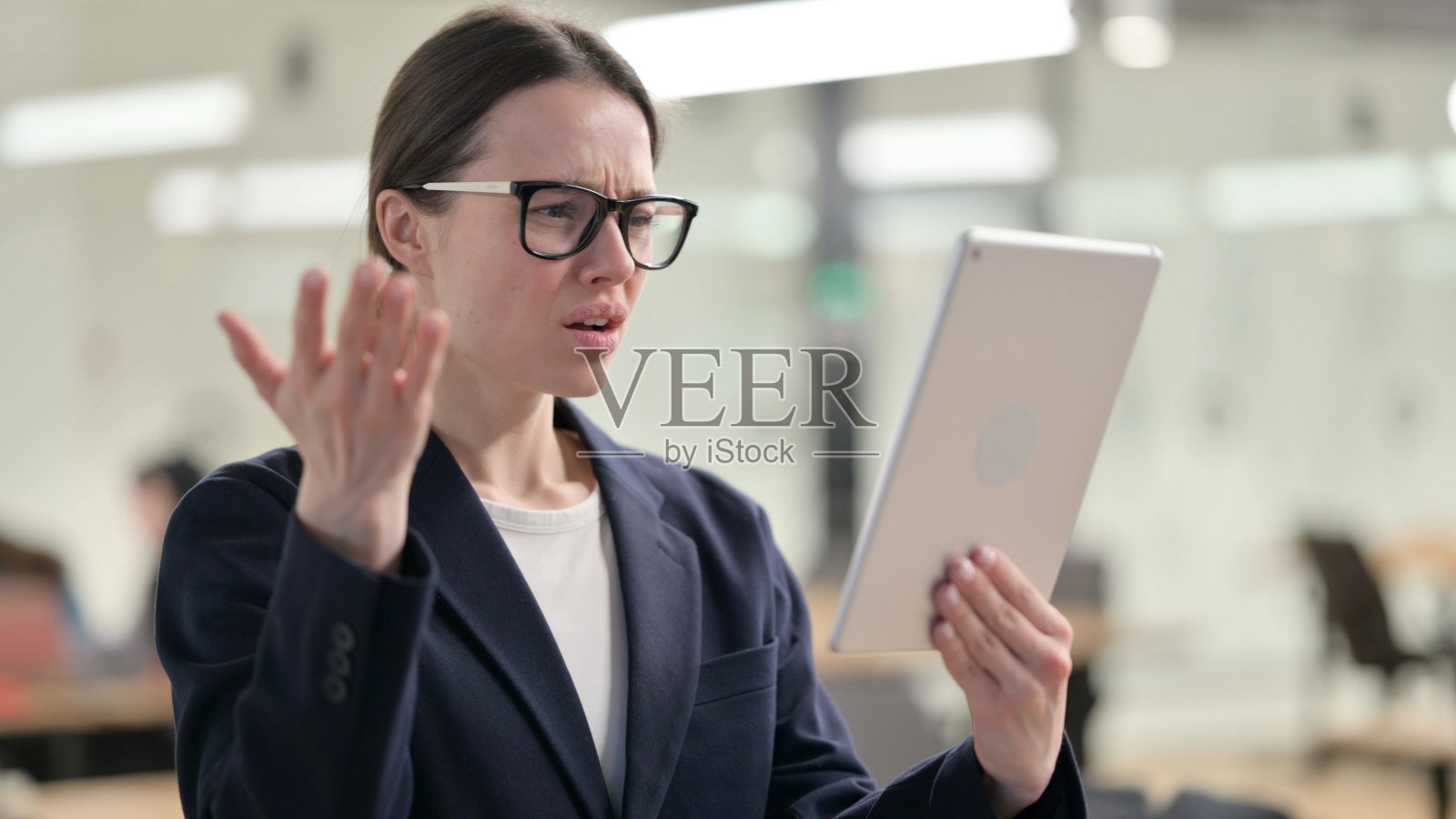 年轻女商人因平板电脑上的损失而沮丧照片摄影图片