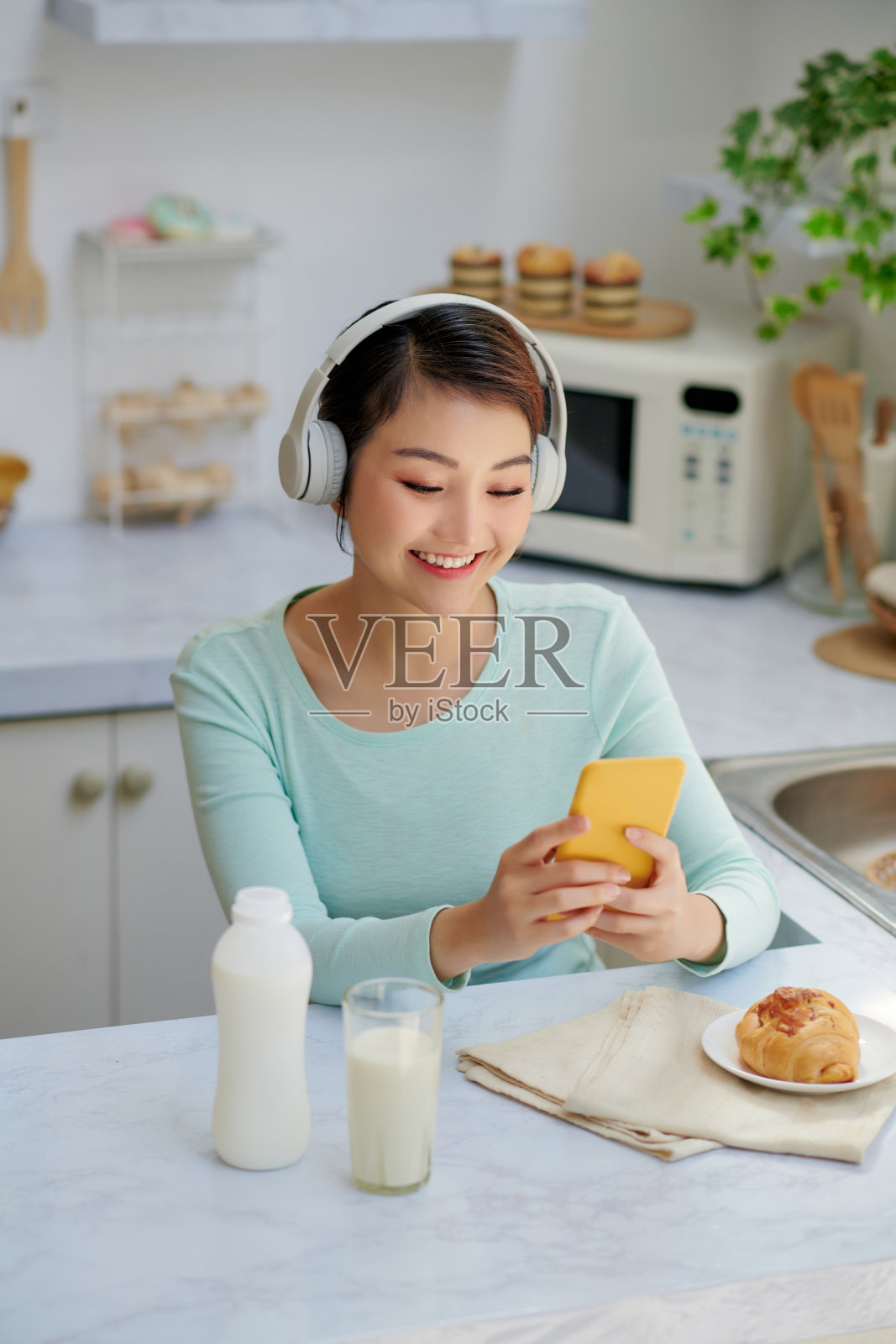 年轻女子使用智能手机和无线耳机与朋友进行视频通话照片摄影图片