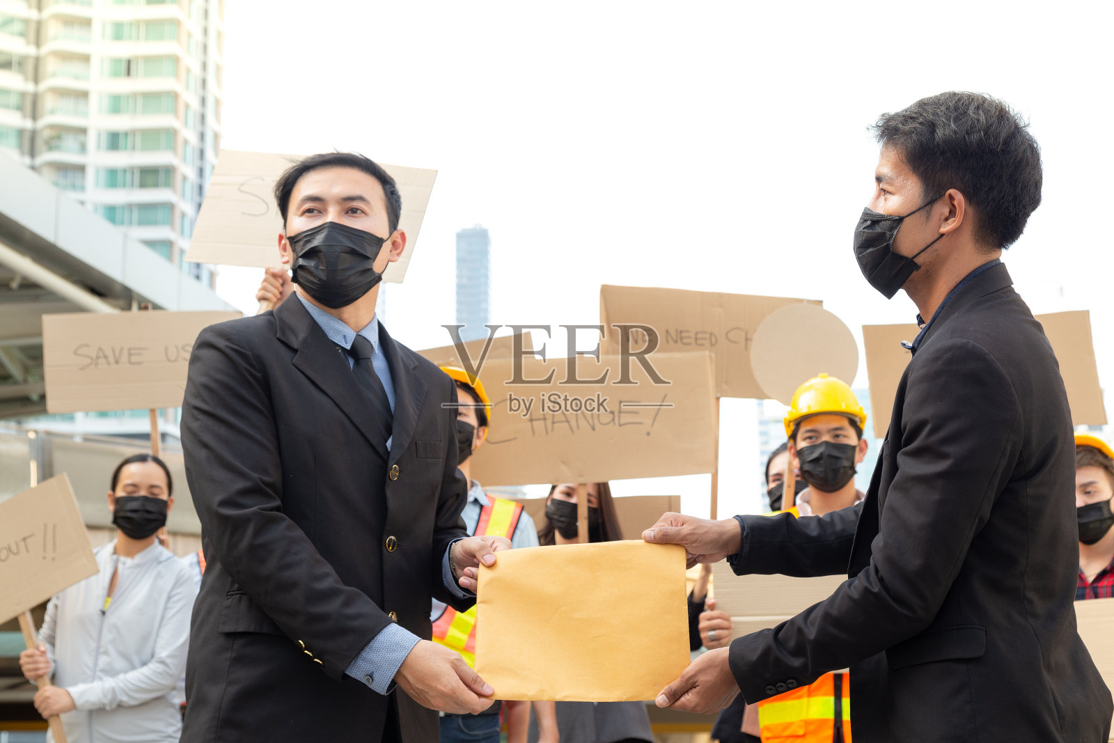 戴着口罩的年轻人在集会上提交主张保护环境的文件，并高喊口号。一群示威者在城市中抗议。抗议活动。照片摄影图片