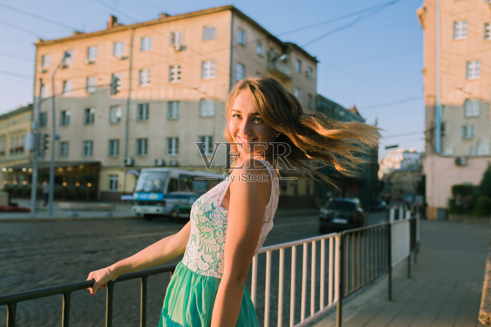 可爱的金发女人与迷人的微笑在日出和太阳眩光摆姿势照片摄影图片