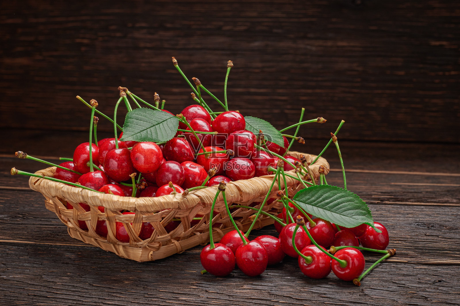木桌上放着一个装满成熟樱桃的篮子照片摄影图片