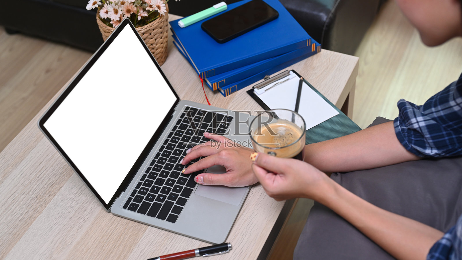 剪短的照片女人拿着一杯咖啡，在家里用笔记本电脑工作。照片摄影图片