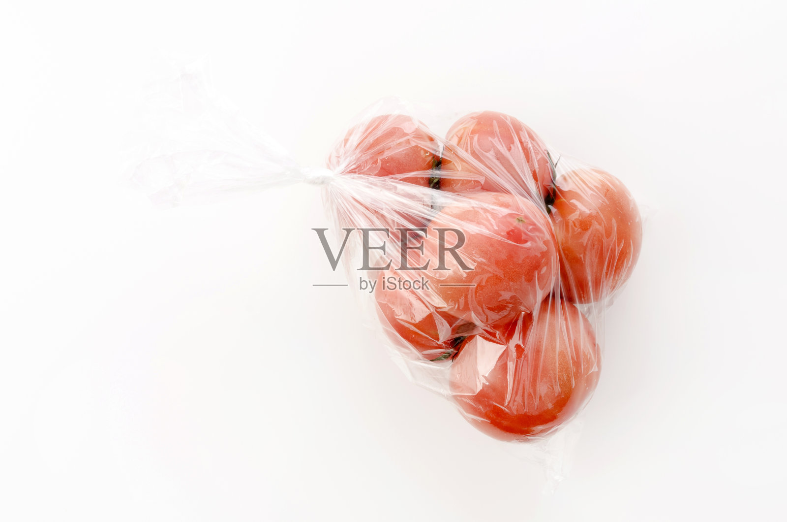 熟透的红番茄装在塑料袋里，白色背景照片摄影图片