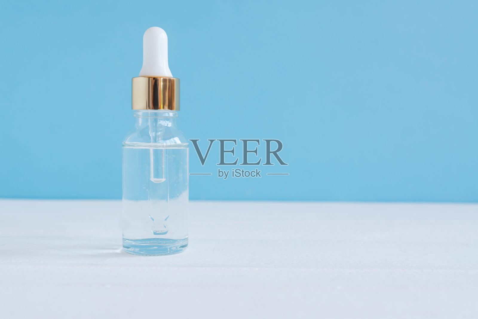 琥珀色玻璃，蓝色底色的血清瓶。适合年轻肌肤的时尚美容产品。额外的保湿步骤在每天的面部常规。照片摄影图片