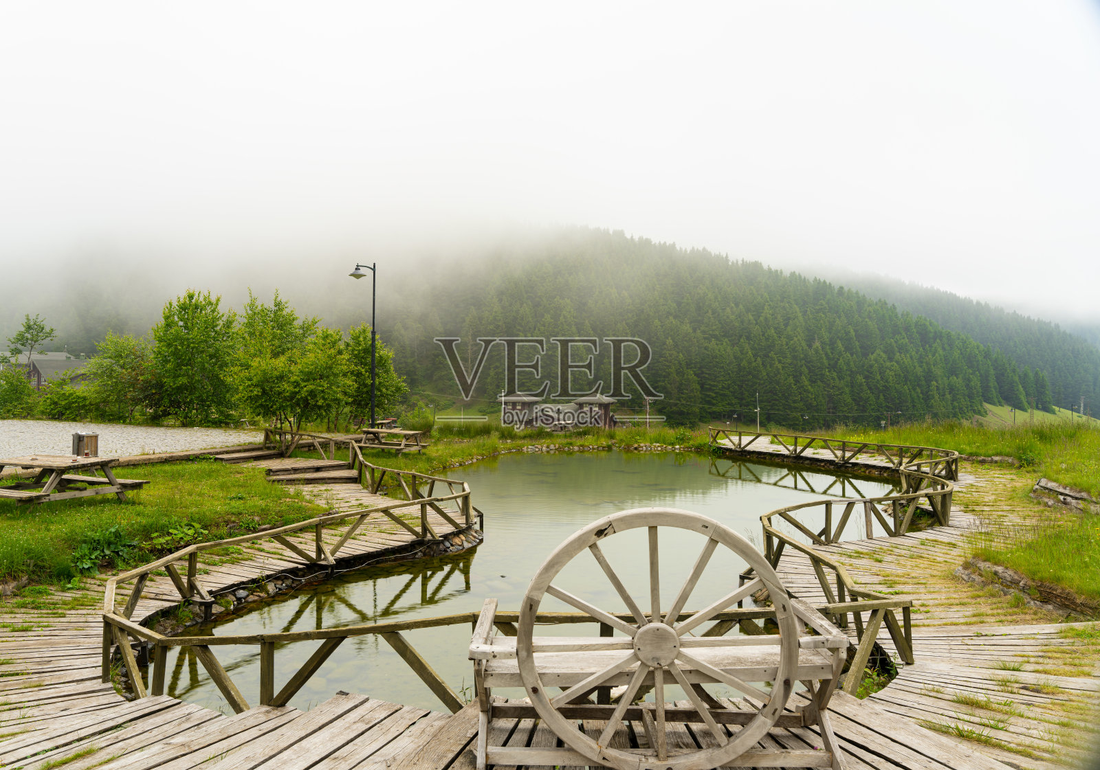 雾气蒙蒙的天气，自然的山景，一个小人工湖被一条木制的步道环绕着，提供了一个完美的视野照片摄影图片