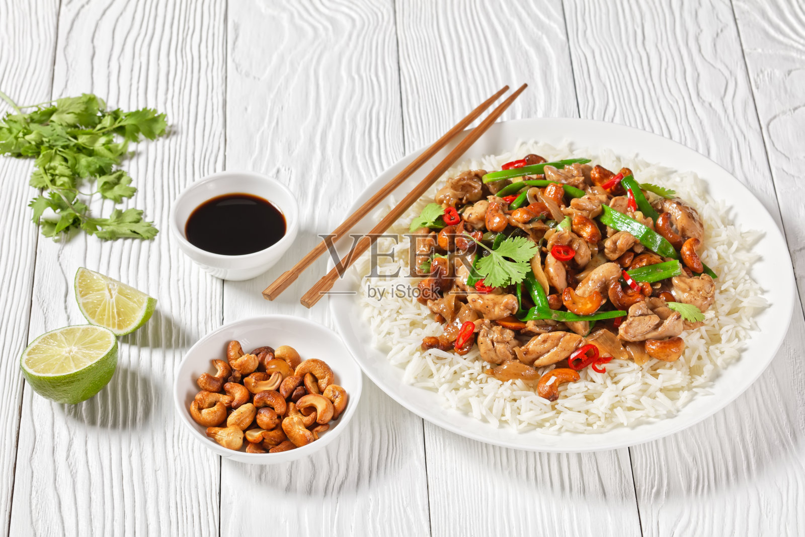 泰式腰果鸡和茉莉花饭一起炒，放在木桌上用筷子夹着的白色盘子里，从上面水平看，特写照片摄影图片