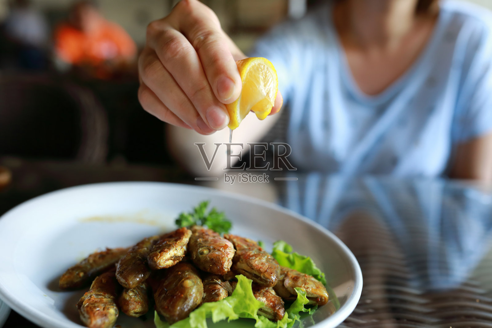 人洒柠檬汁炒红鲻鱼照片摄影图片