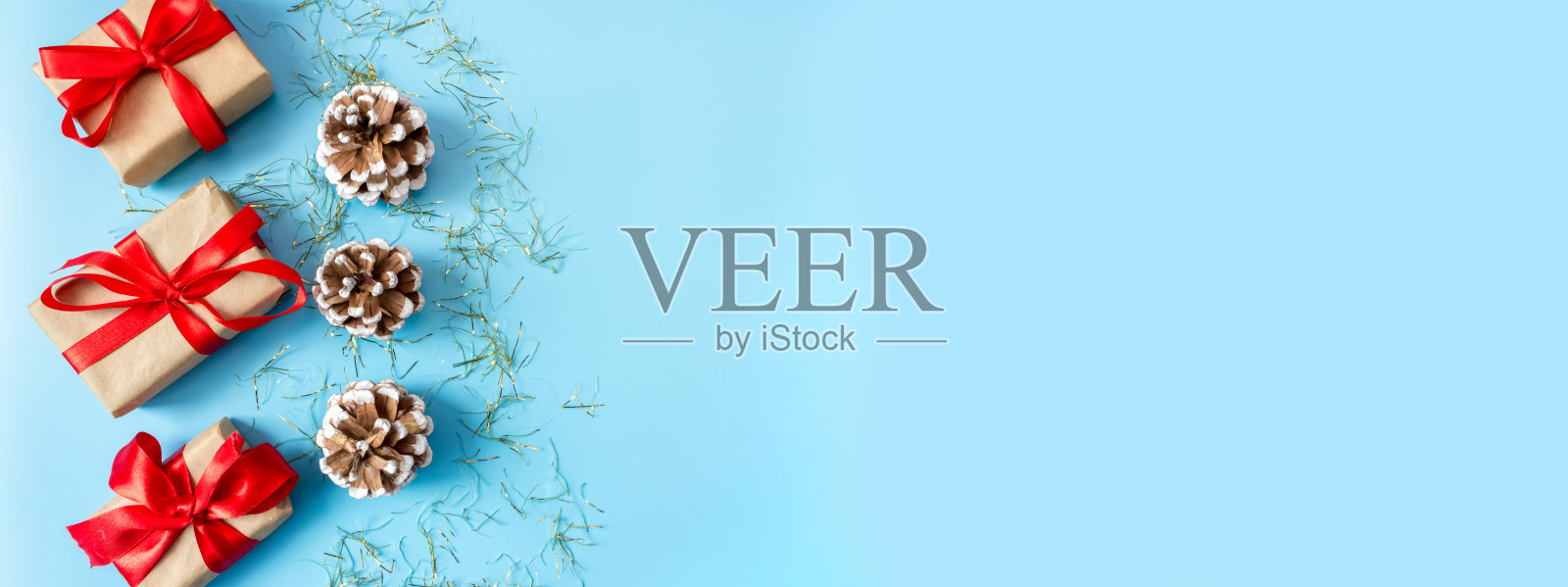 蓝色背景上有红色蝴蝶结和松果的礼盒。照片摄影图片