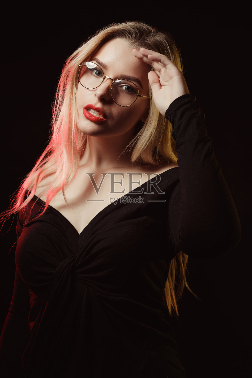 戴眼镜的时髦金发模特穿着一件露肩衬衫照片摄影图片