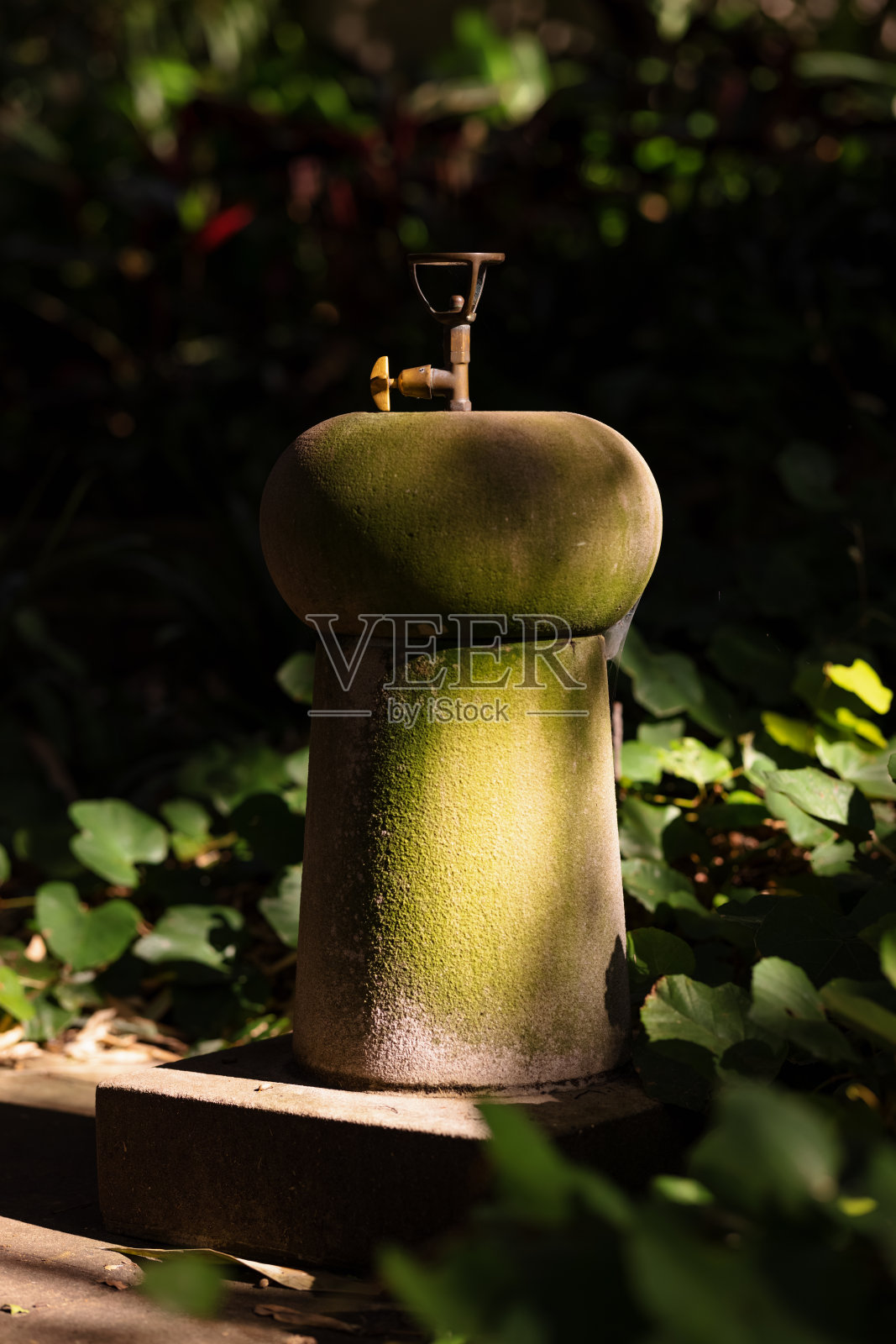 古老的石头饮水机在部分阴影照片摄影图片