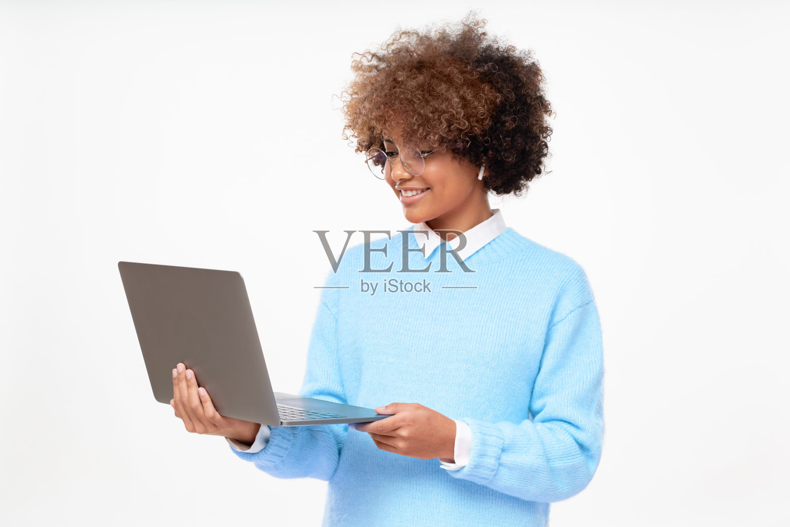 在线课程学生的工作室肖像，微笑的非洲裔美国少女，拿着笔记本电脑，孤立在灰色的背景照片摄影图片