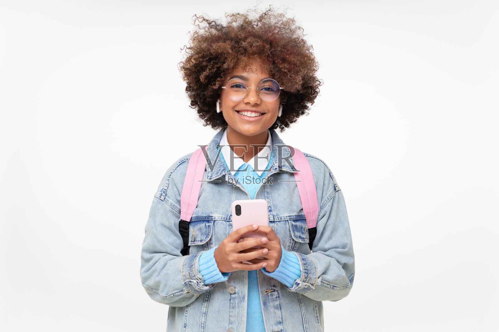 非洲裔美国大学女孩微笑着，留着非洲式发型，戴着时髦的眼镜，拿着智能手机，看着相机，孤立在灰色的背景照片摄影图片