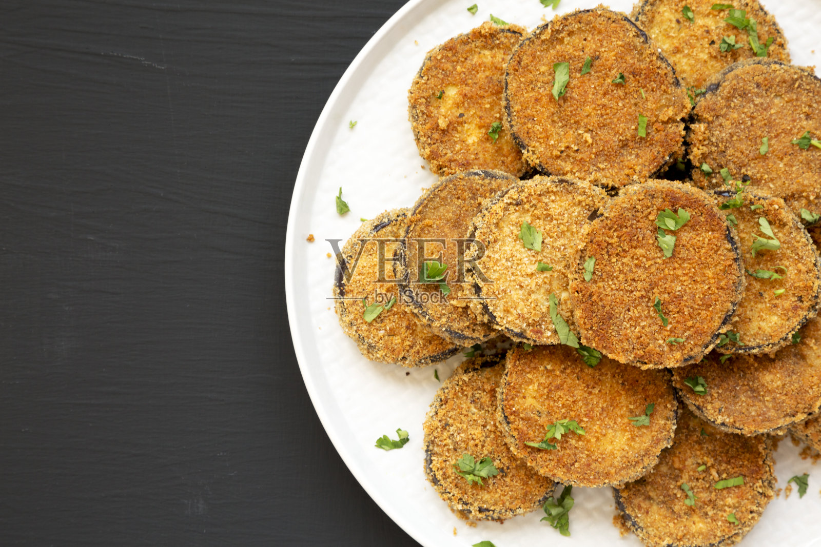 在黑色背景的盘子上自制的大蒜帕尔马干酪烤茄子，俯视视图。平躺，俯视图，从上面。副本的空间。照片摄影图片