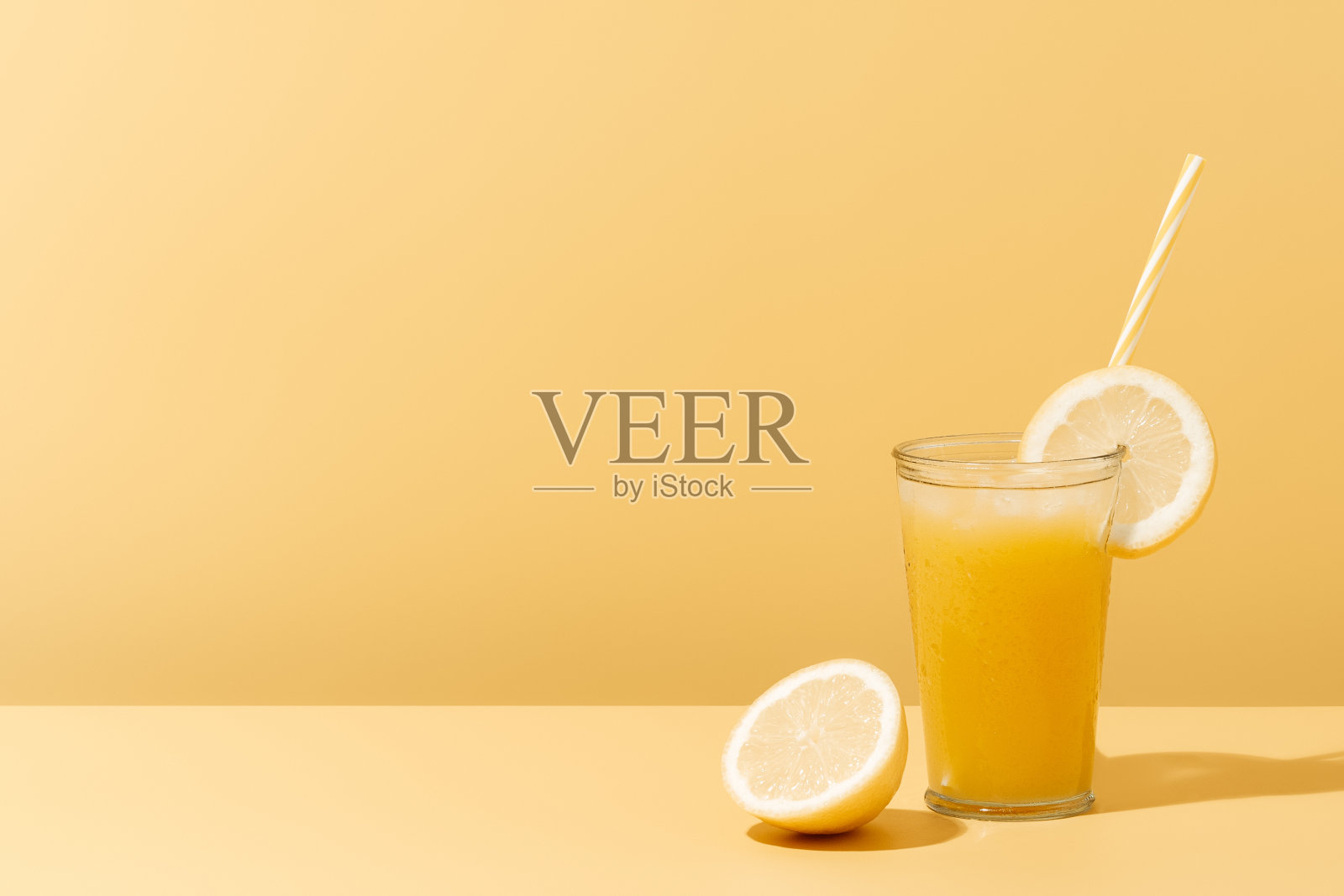 夏日的黄色背景上，一杯柠檬和吸管的清爽果汁。照片摄影图片