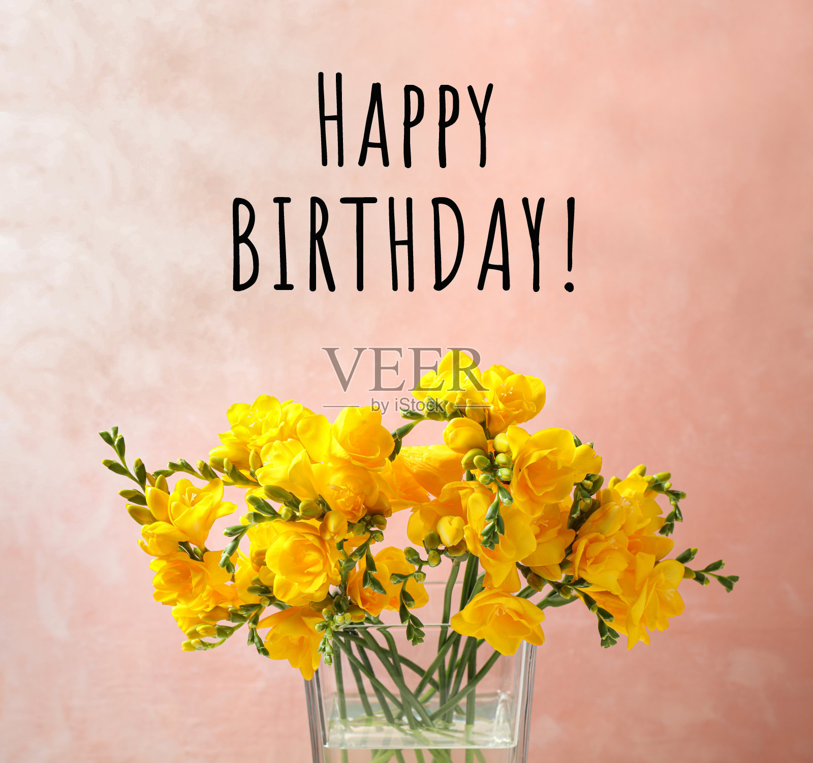 生日快乐!美丽的黄色小苍兰花在玻璃花瓶在粉红色的背景照片摄影图片