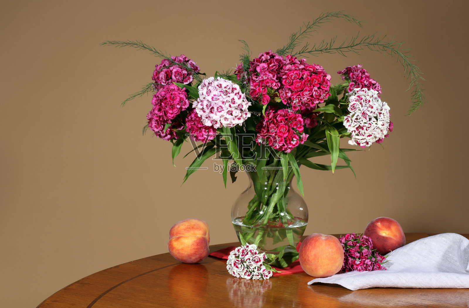 米色背景上放着夏季鲜花和桃子的花瓶照片摄影图片