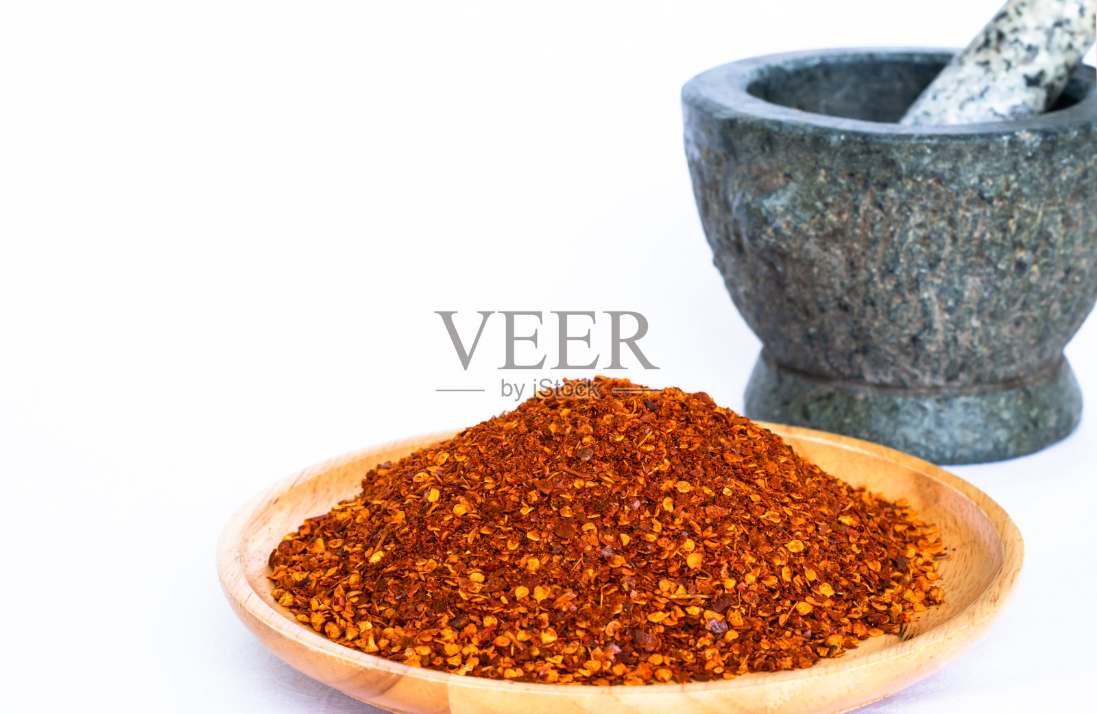 辣椒粉放在圆木托盘上，后面是模糊的灰浆。照片摄影图片