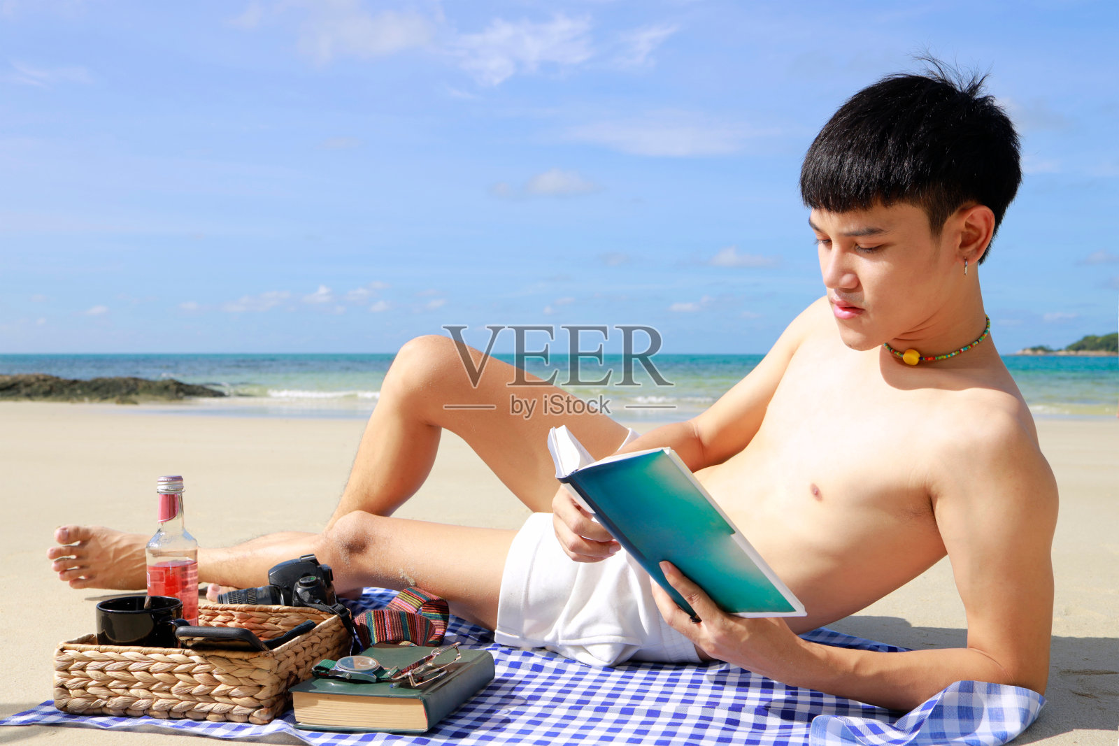 男人在海滩上悠闲地读着书度过夏天。照片摄影图片