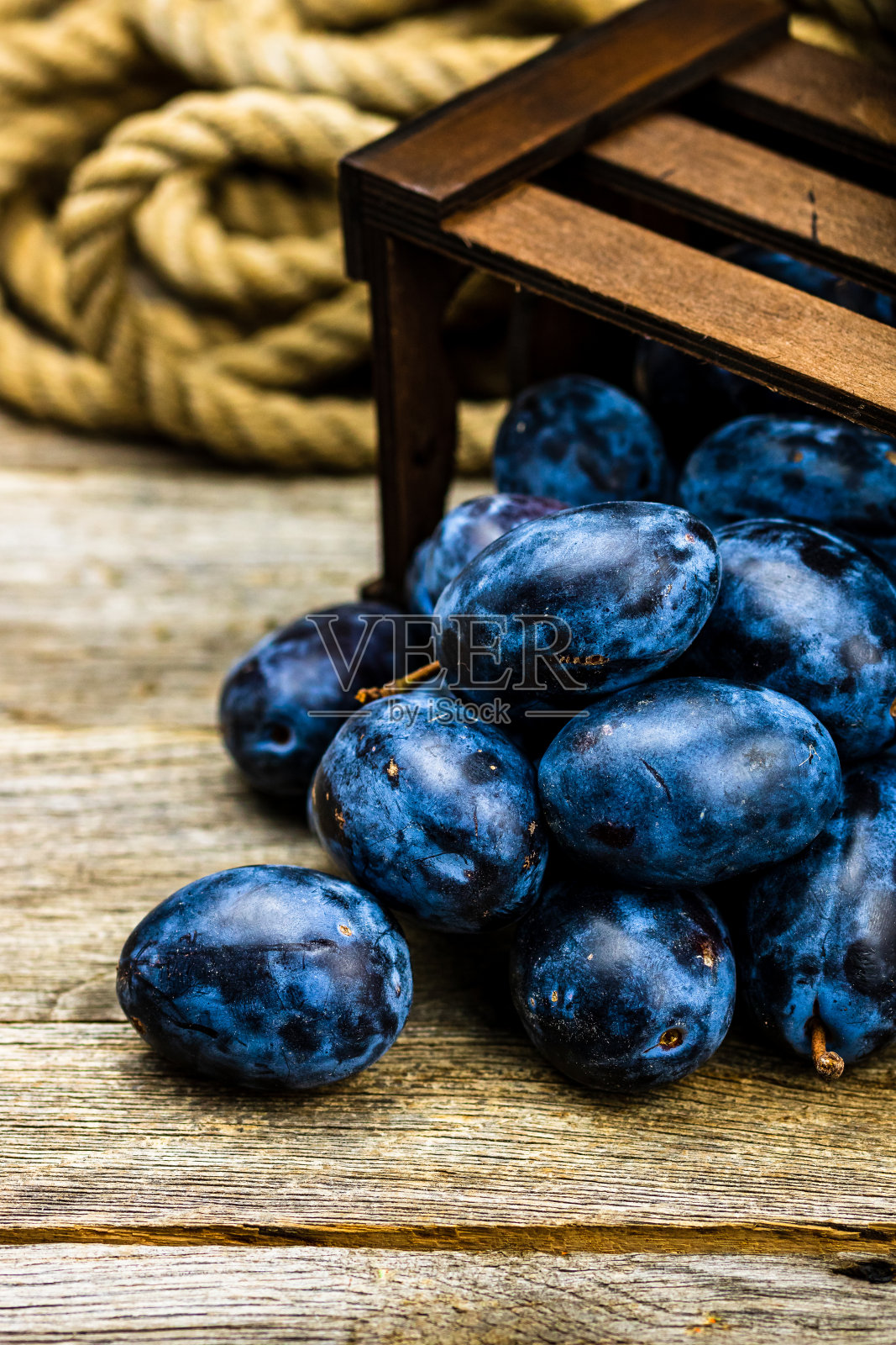 成熟的蓝李子在一个乡村的木条箱。照片摄影图片