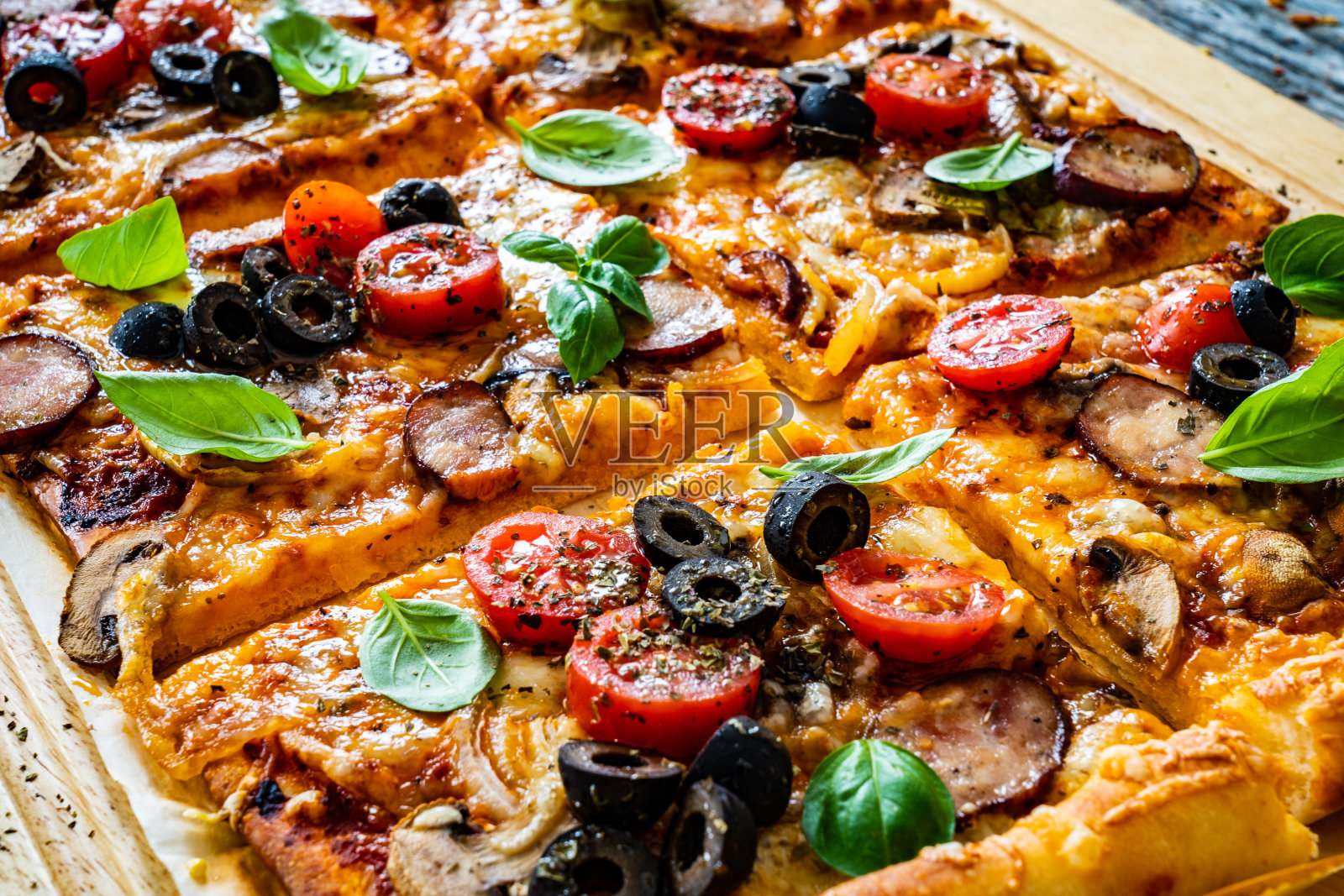 美味的玛格丽塔披萨与火腿，白蘑菇，马苏里拉奶酪和蔬菜在木制背景照片摄影图片