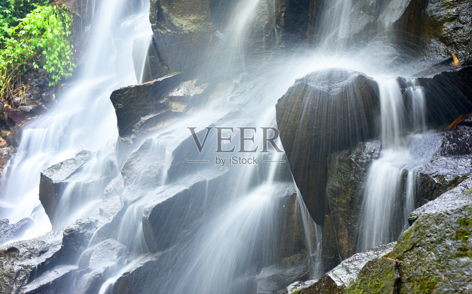 Kanto Lampo瀑布在印度尼西亚巴厘岛的Gianyar摄政，清澈的水和黑色的岩石。照片摄影图片