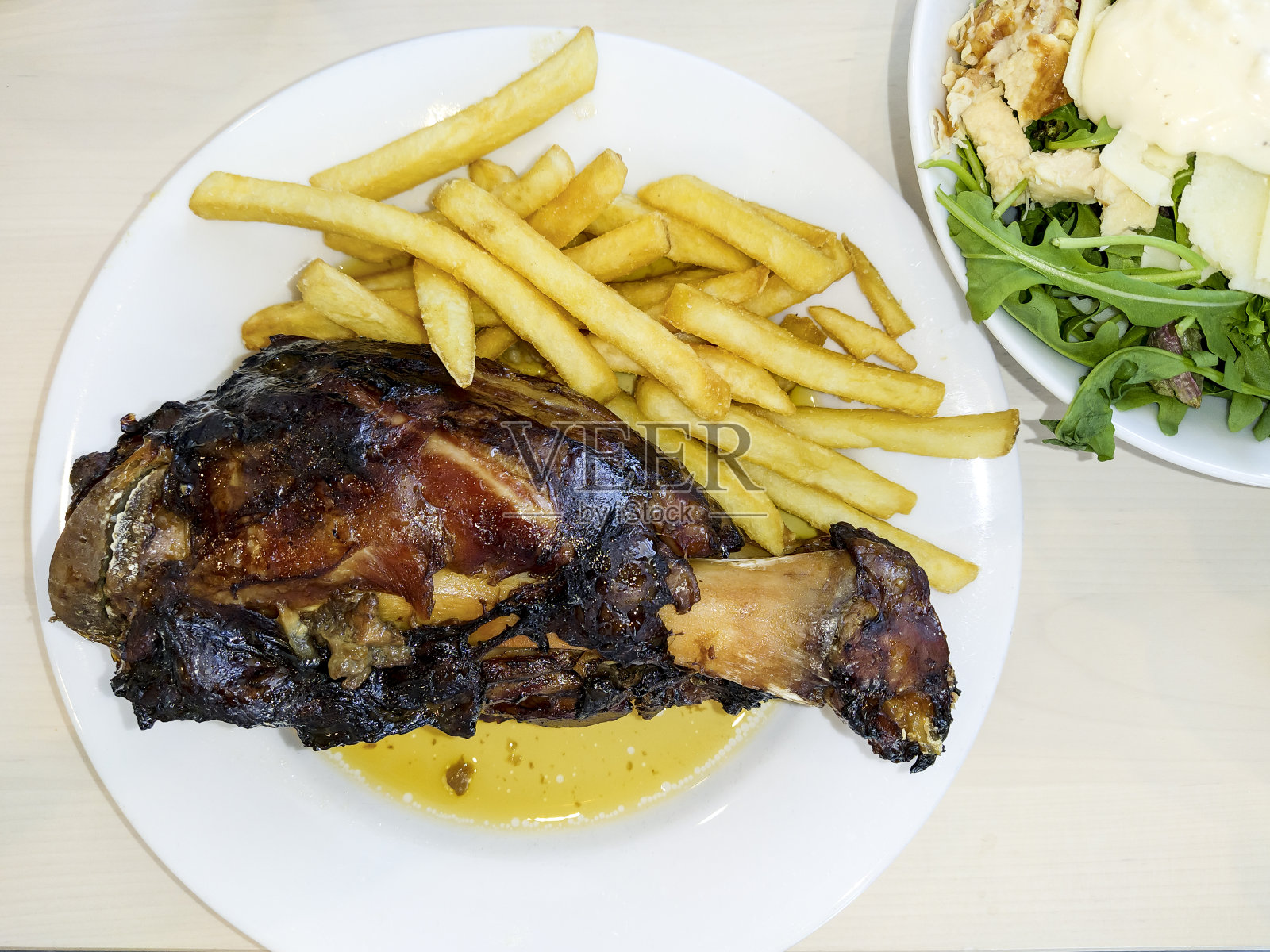 肉汁猪蹄配炸土豆，再配上美味的沙拉，这是宜家餐厅最受欢迎的菜肴。西班牙萨拉戈萨。照片摄影图片