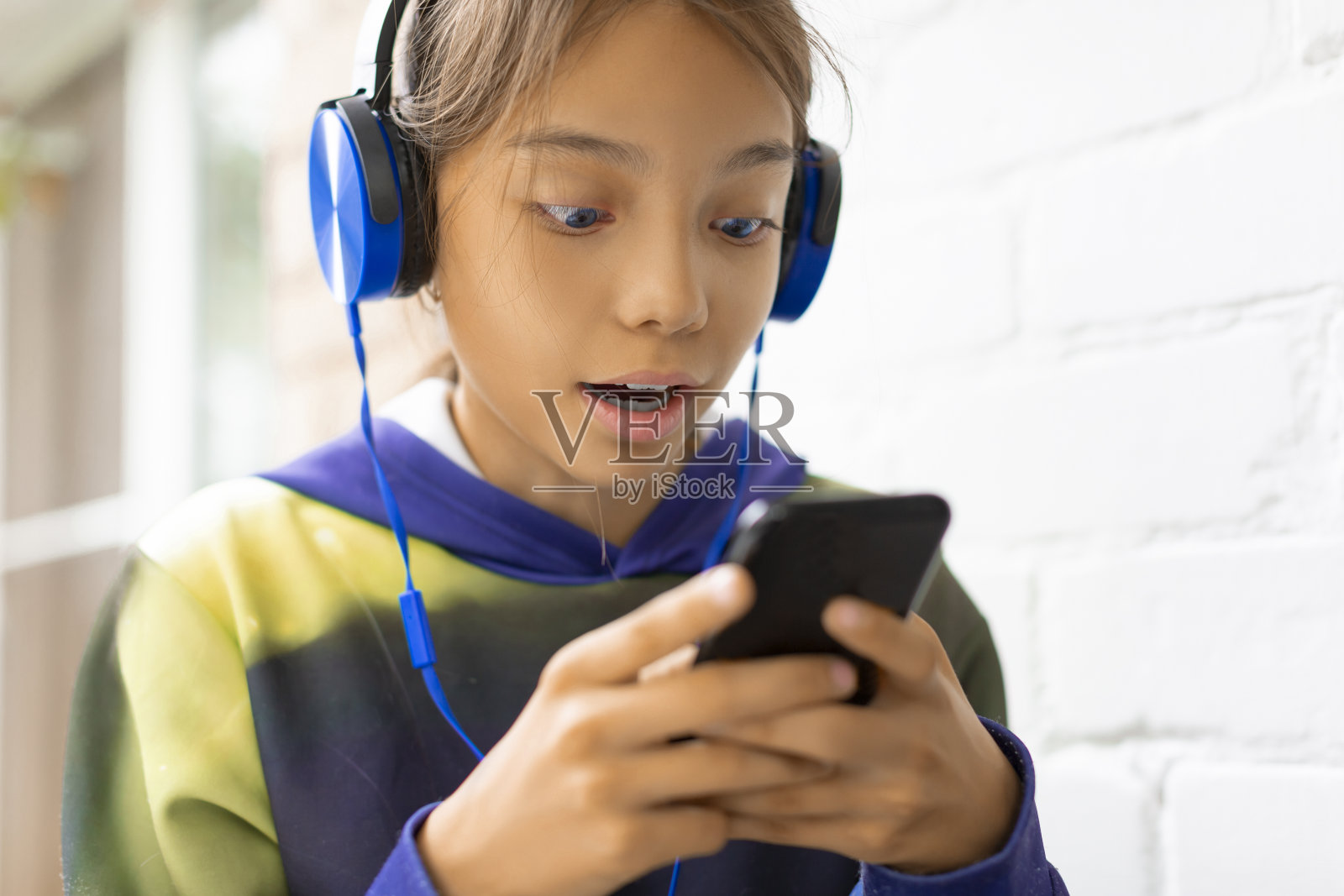 戴着蓝色耳机与朋友在线聊天的青少年女孩特写照片摄影图片