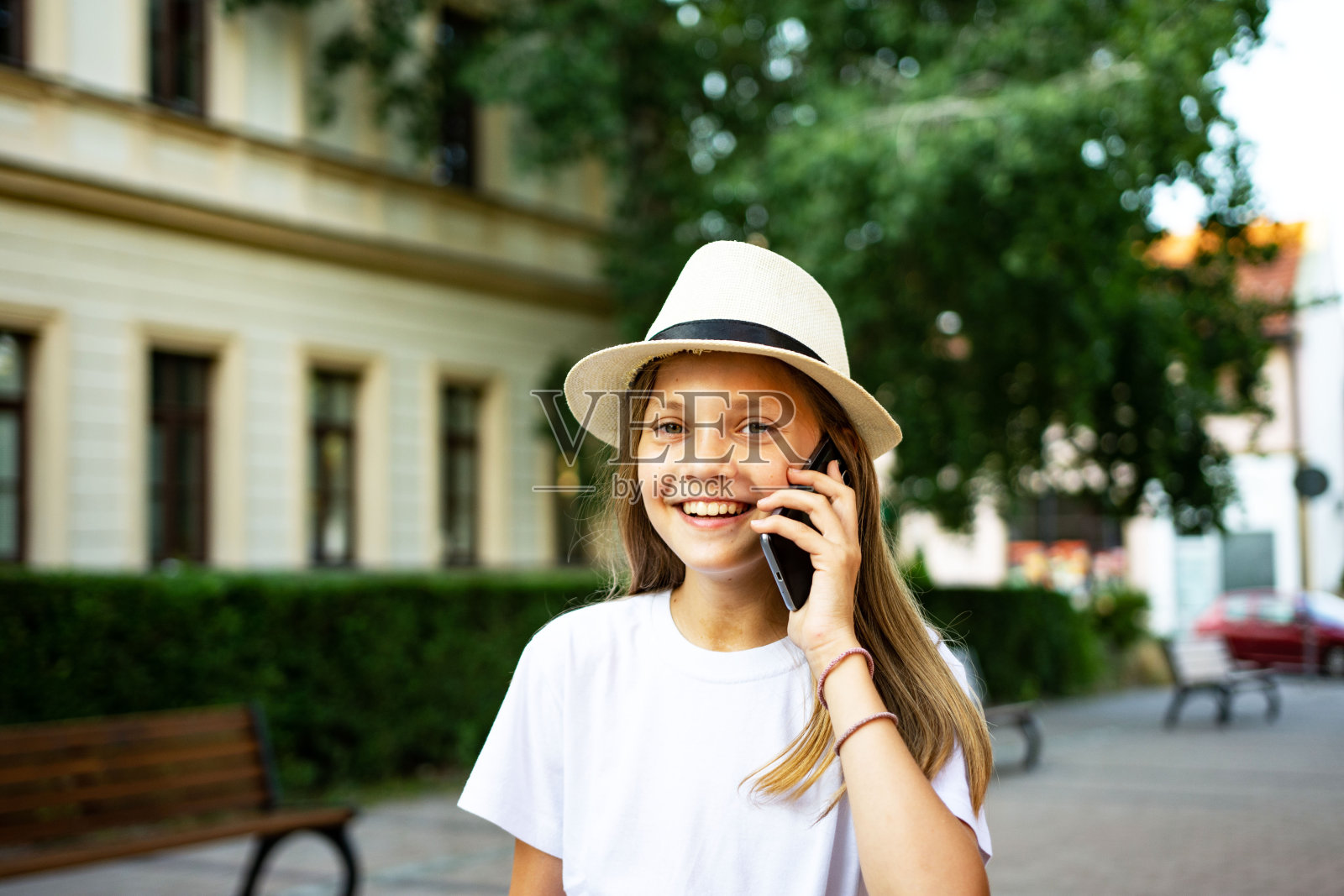 漂亮的十几岁的女孩戴着太阳帽走在城市的街道上打电话照片摄影图片