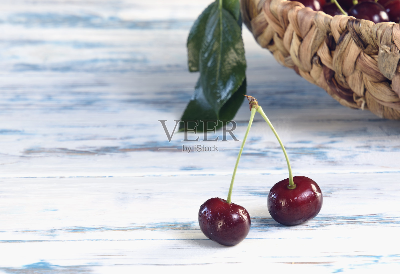 一对成熟的樱桃茎，与水分，水，在一个轻木制桌子上近距离，聚焦在前景照片摄影图片