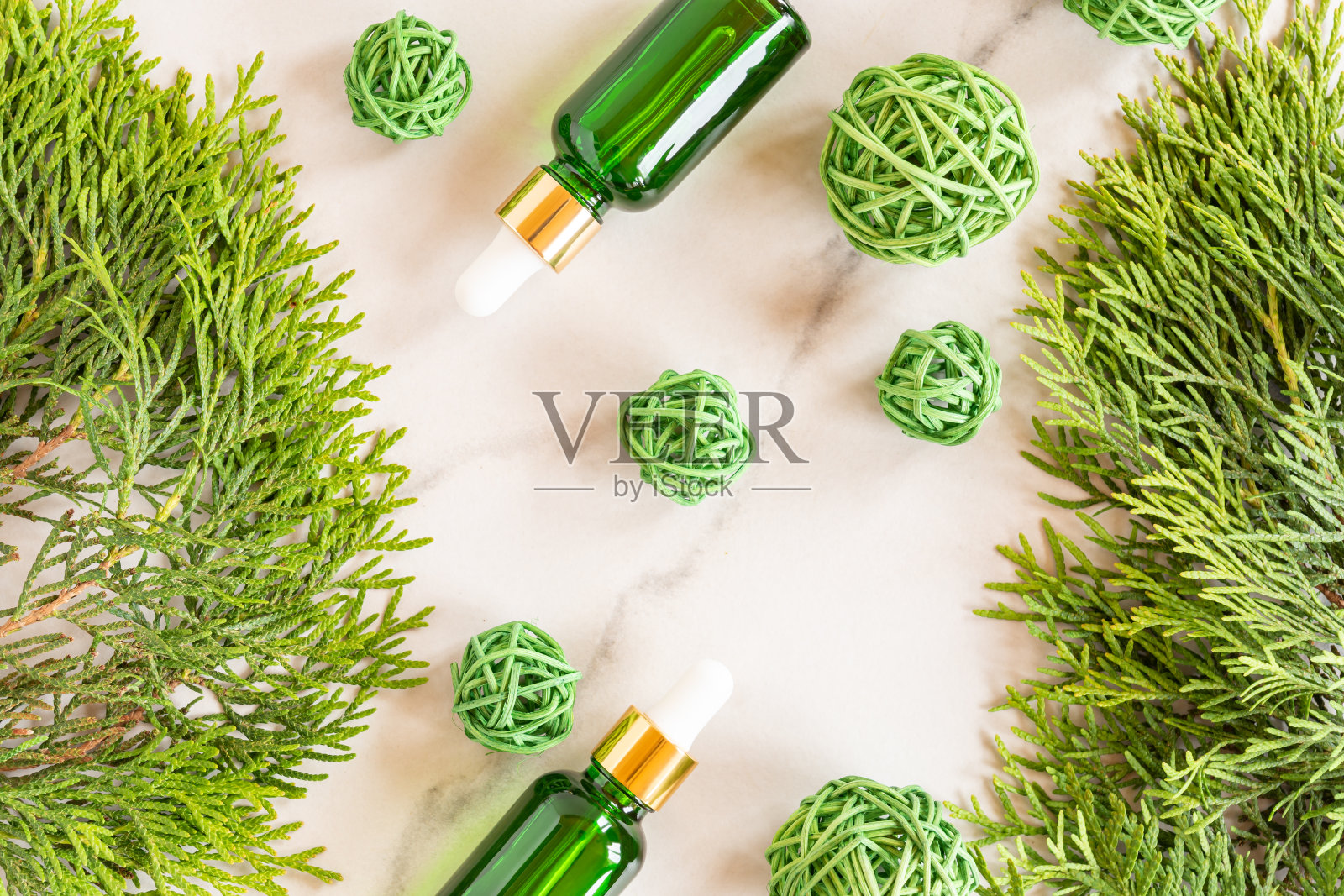 绿色玻璃滴管瓶与化妆品油，精华或血清在大理石背景与thuja树枝和ratang球。天然有机化妆品的概念。草药顺势疗法的产品。照片摄影图片