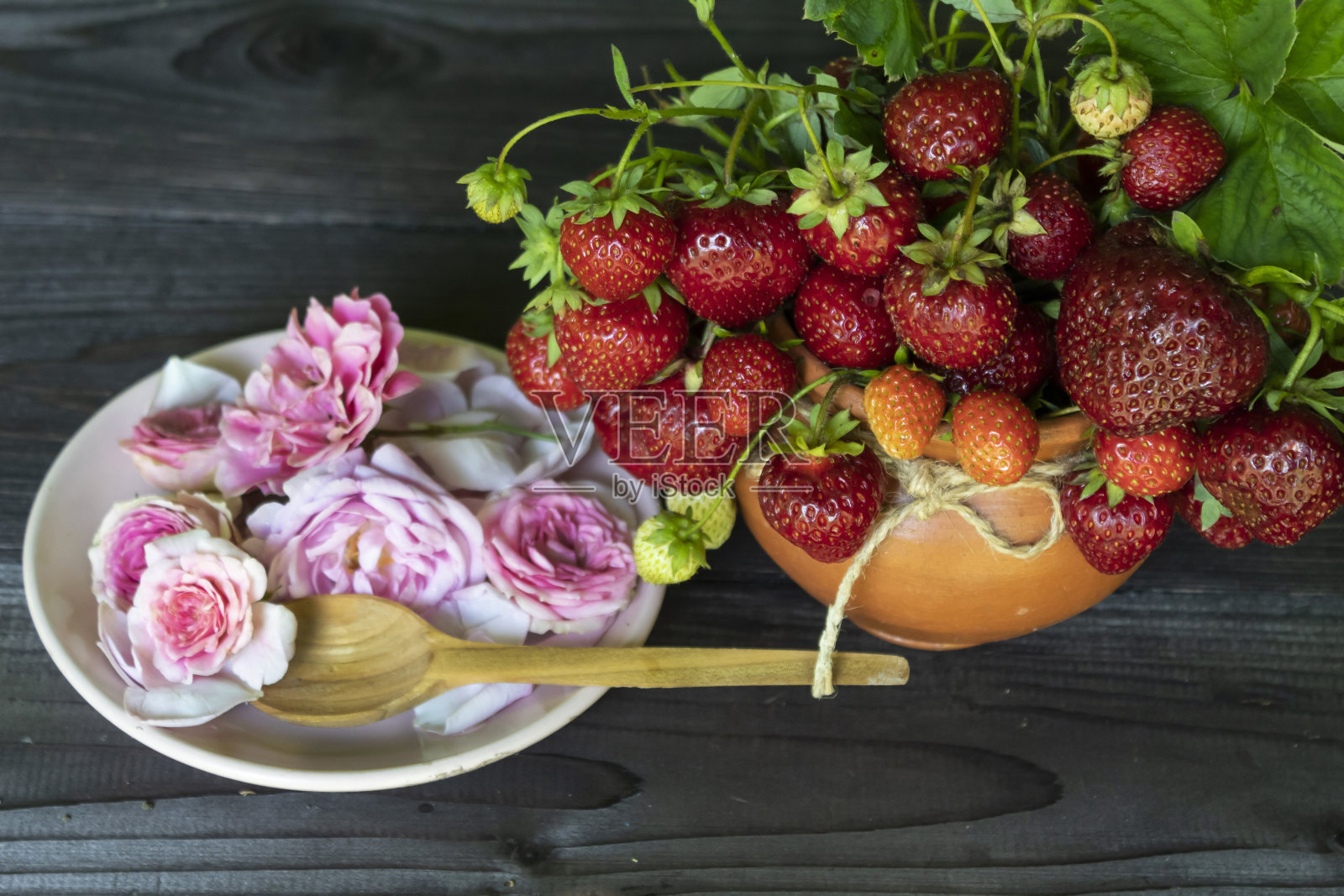 有一束成熟的红草莓和一盘粉红色的玫瑰照片摄影图片