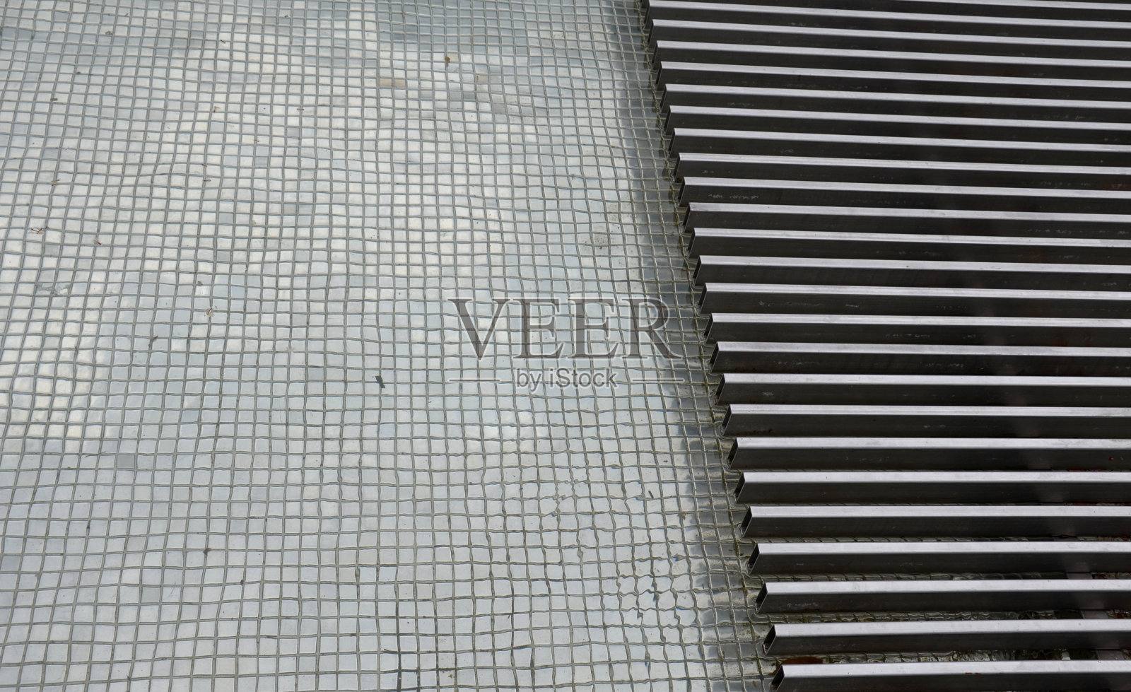 广场上的喷泉用马赛克瓷砖砌成。通过由金属不锈钢板条制成的科学平台或桥。桥是透明的。多亏了喷泉和喷泉，水很干净照片摄影图片