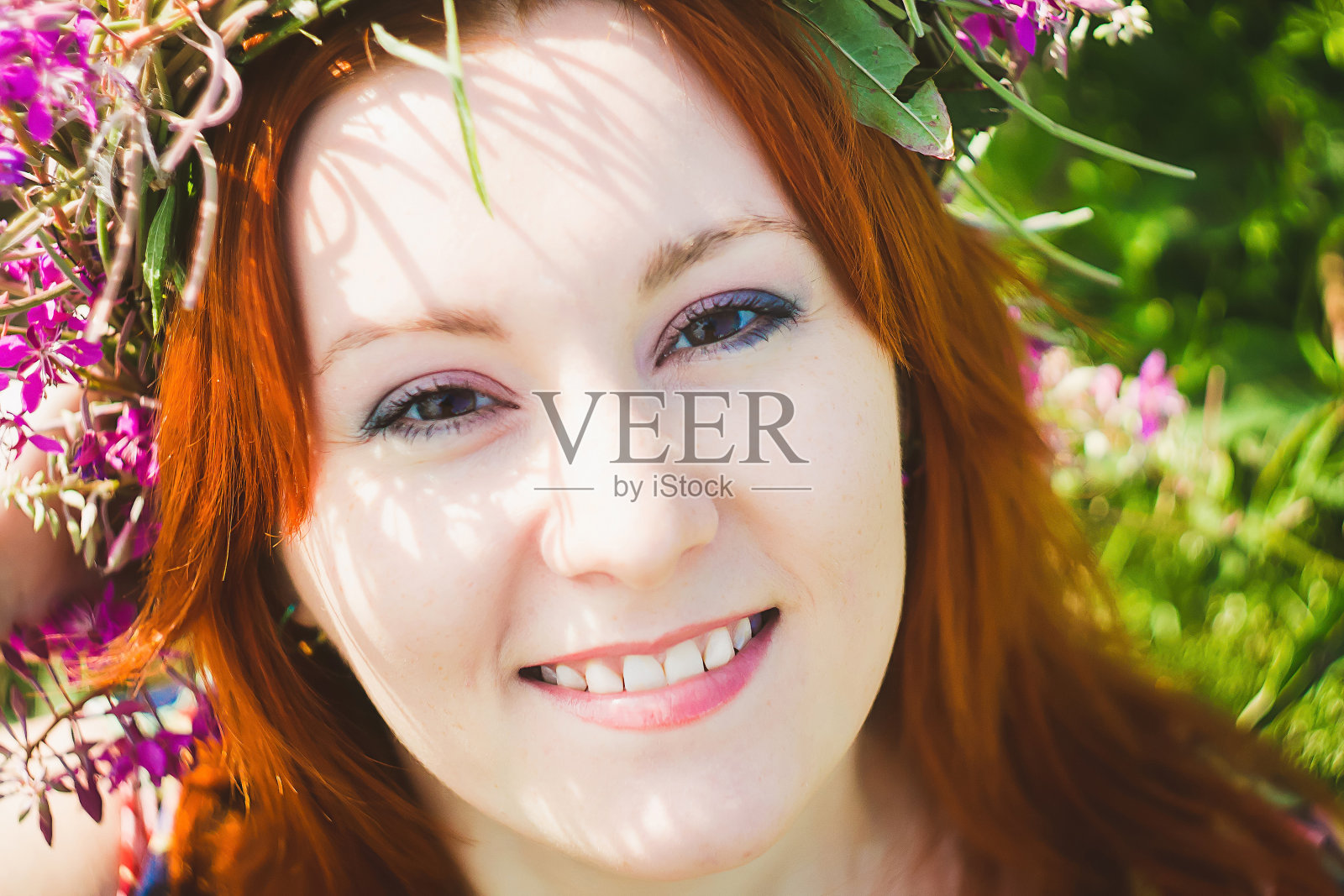 年轻美丽的红发女子的肖像，头上戴着粉红色的花环。有吸引力的女士微笑。夏天的风格照片摄影图片