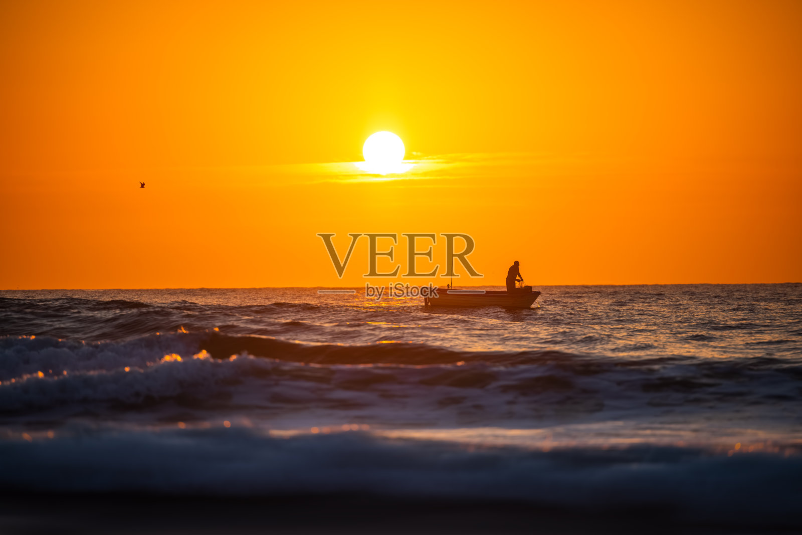 渔夫和他的船在美丽的日出海上航行照片摄影图片